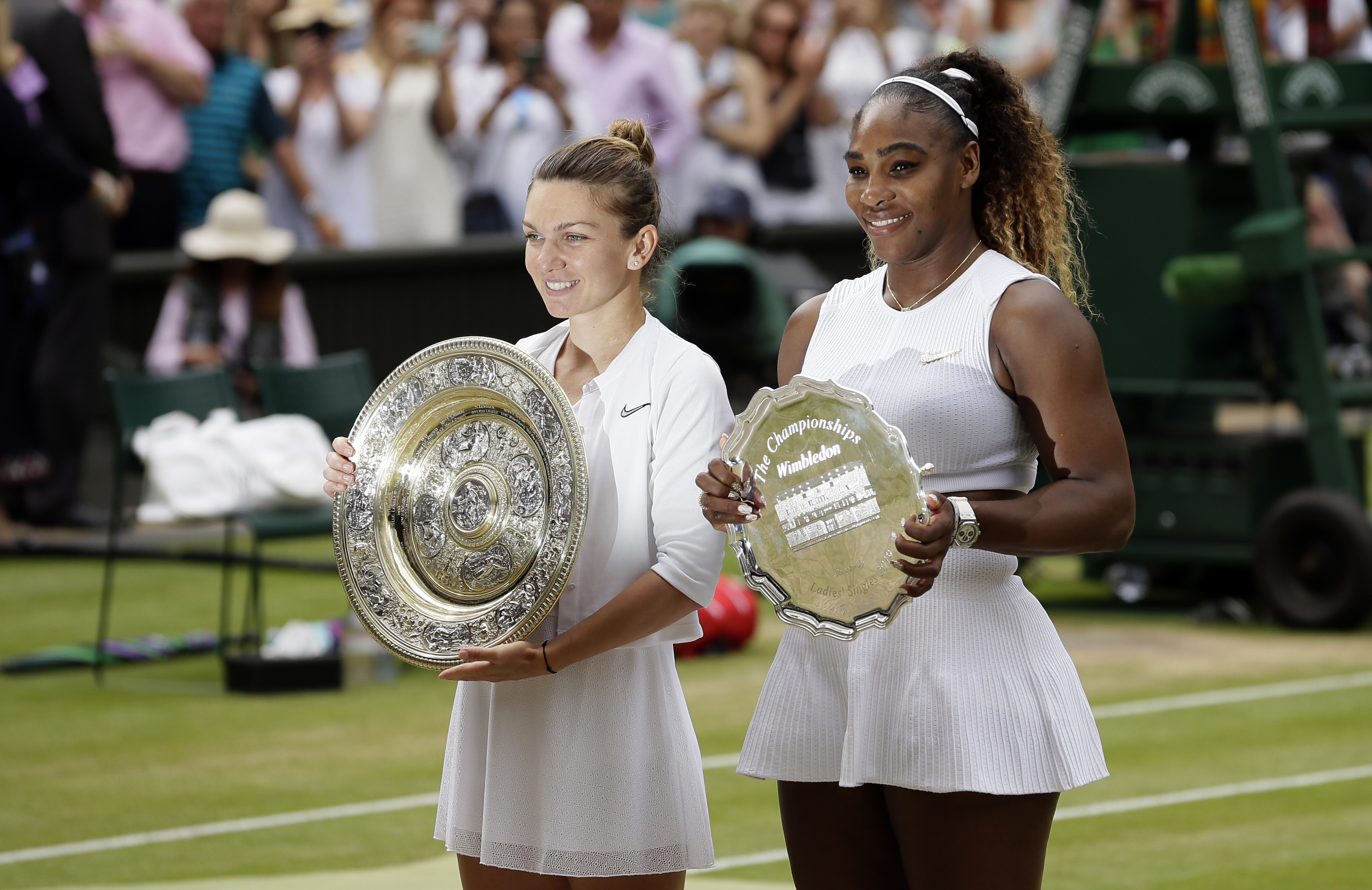 FILE - Winner Romania's Simona Halep and second placed United States' Serena Williams, right, pose with their trophies after the women's singles final match on day twelve of the Wimbledon Tennis Championships in London, July 13, 2019.