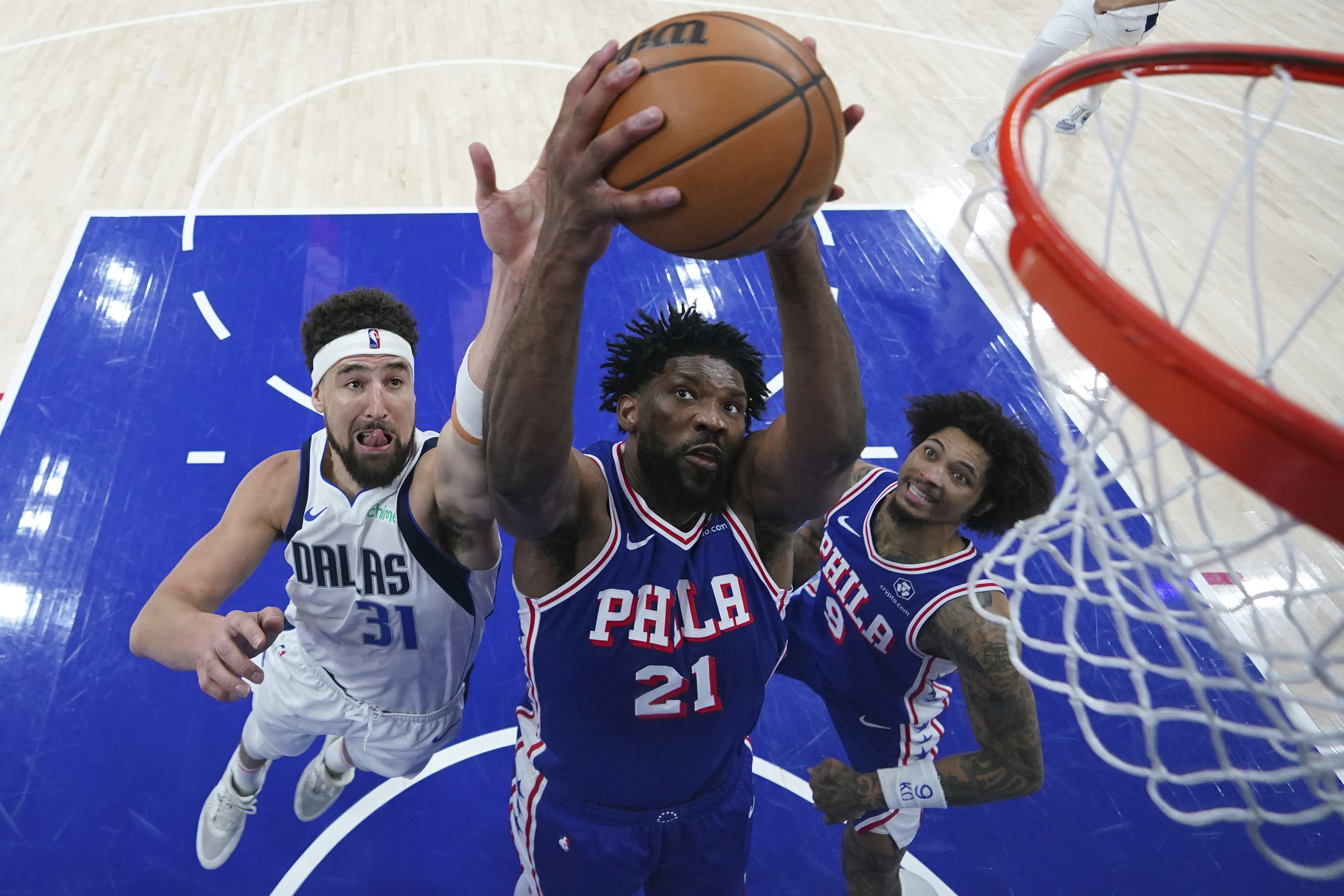 Philadelphia 76ers' Joel Embiid, center, pulls in a rebound between Dallas Mavericks' Klay Thompson, left, and Kelly Oubre Jr. during the second half of an NBA basketball game, Tuesday, Feb. 4, 2025, in Philadelphia.