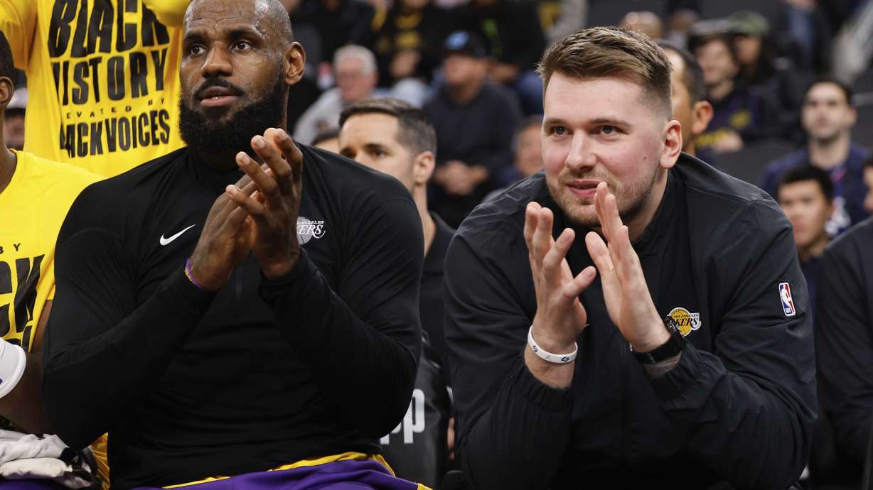 Los Angeles Lakers guard Luka Doncic, right, sits next to forward LeBron James on the bench before an NBA basketball game against the Los Angeles Clippers, Tuesday, Feb. 4, 2025, in Inglewood, Calif.