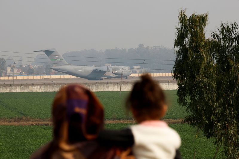 People look at a U.S. military plane deporting Indian immigrants as it lands in Amritsar, India, Wednesday.