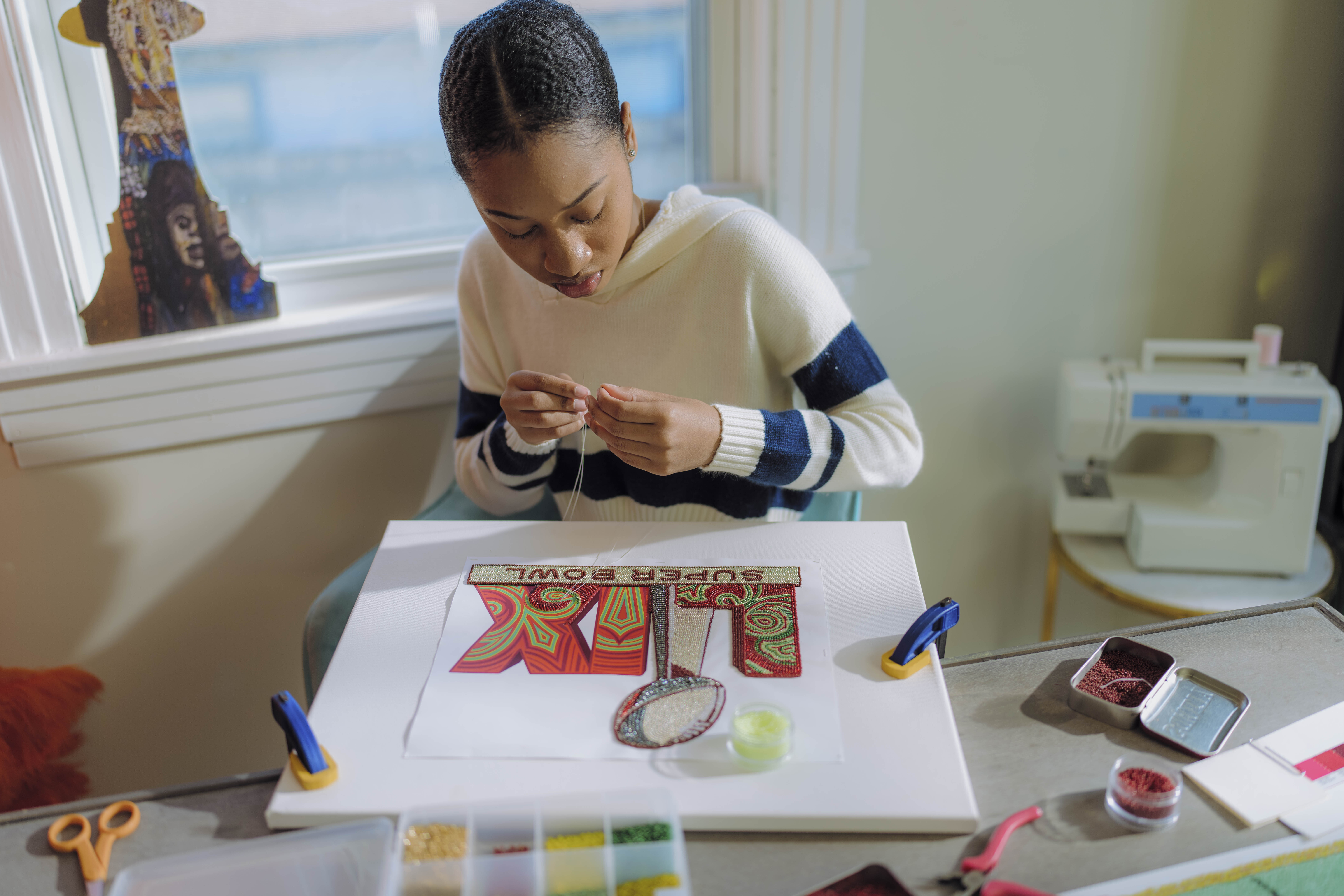 In this undated photo provided by the NFL, New Orleans artist Tahj 'Queen Tahj' Williams works on the Super Bowl logo.