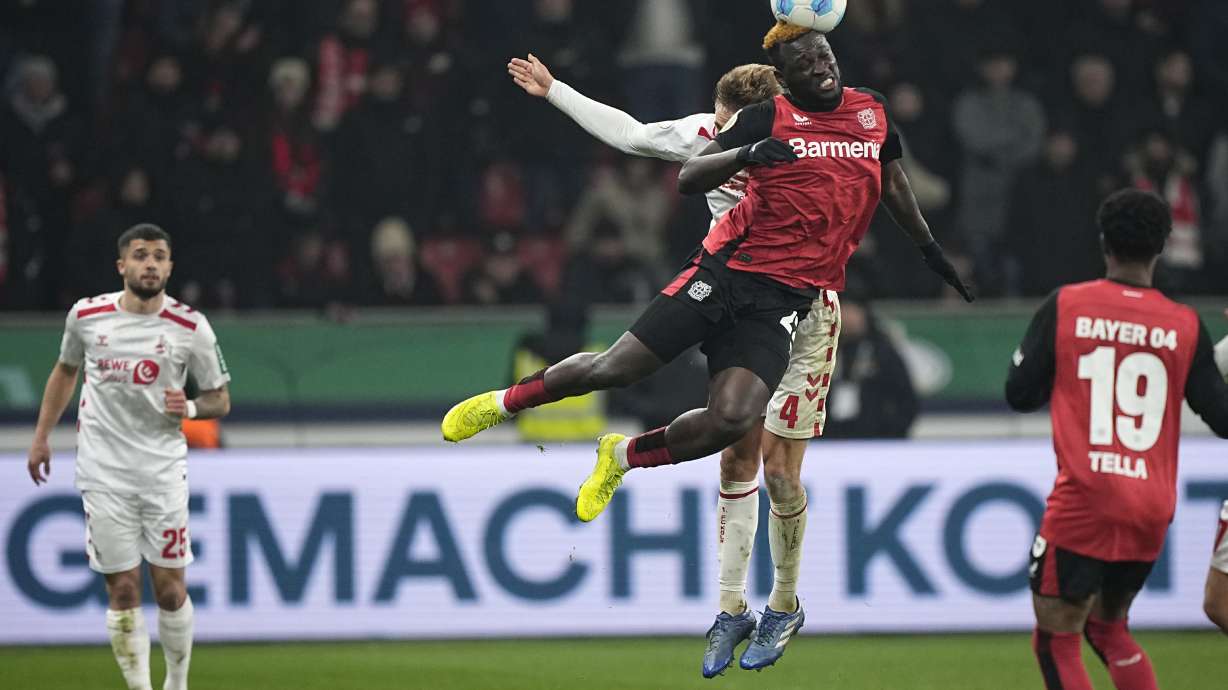 Leverkusen's Victor Boniface, front, and Cologne's Timo Huebers, rear, jump for a head during the German Cup, quarterfinal soccer match between Bayer Leverkusen and FC Cologne at the BayArena in Leverkusen, Germany, Wednesday, Feb. 5, 2025.