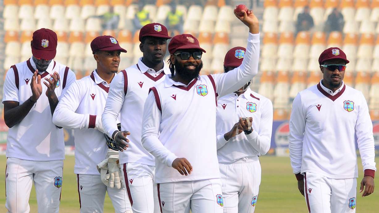 West Indies Jomel Warrican, center, who took seven wickets in the second innings, raises the ball to acknowledge the crowd during the day three of the first test cricket match between Pakistan and West Indies in Multan, Pakistan, Sunday, Jan. 19, 2025.