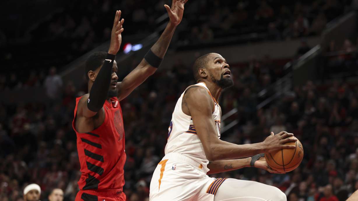 Phoenix Suns forward Kevin Durant, right, drives to the basket past Portland Trail Blazers center Deandre Ayton during overtime of an NBA basketball game Monday, Feb. 3, 2025, in Portland, Ore.