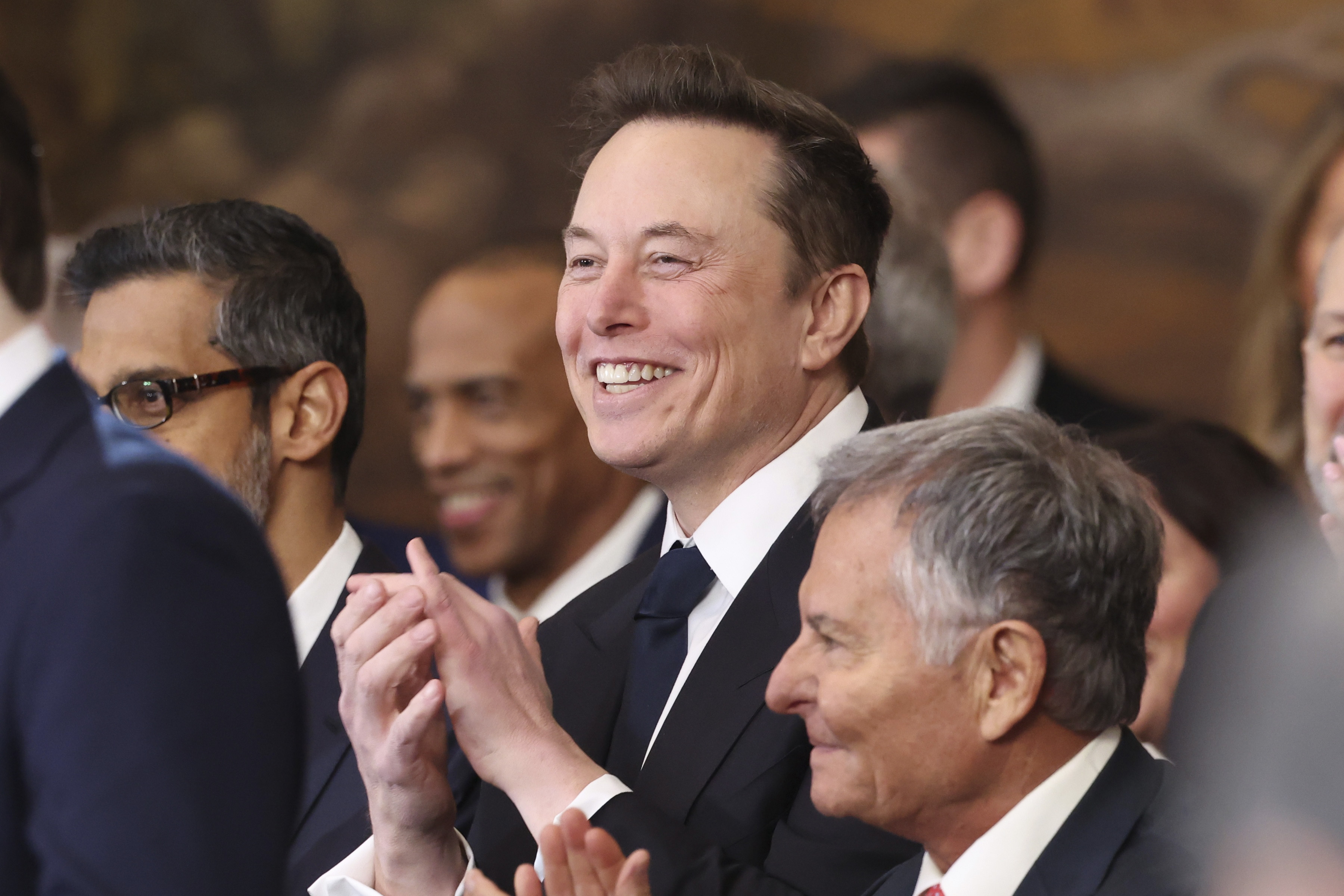 Elon Musk listens as President Donald Trump speaks at the U.S. Capitol Jan. 20. As one of Trump's most powerful advisers, he has orchestrated an unprecedented financial incentive for people to leave their government jobs. A judge blocked the plan Thursday.
