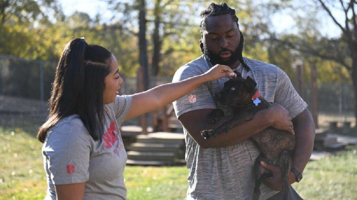Kansas City Chiefs defensive tackle Derrick Nnadi, right, and his girlfriend Nani Hinton, left, pets Parsnip, a puppy from The Humane Society of Greater Kansas City that was featured in the Puppy Bowl XXI, Monday, Oct. 21, 2024, in Kansas City, Kan.