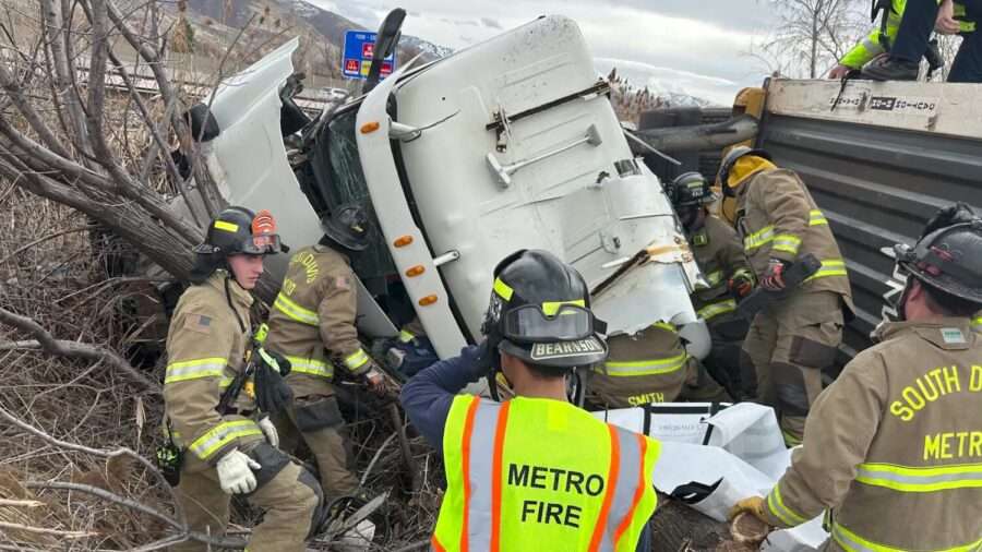 First responders work to free a driver of a semitruck after it hit an embankment on Legacy Parkway, causing it to flip and pin the driver side on Tuesday.