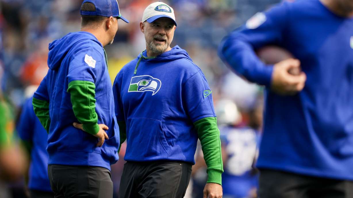 FILE - Seattle Seahawks then-offensive coordinator Ryan Grubb, center, talks with offensive assistant Zak Hill, left, before an NFL football game against the Denver Broncos, Sept. 8, 2024, in Seattle.