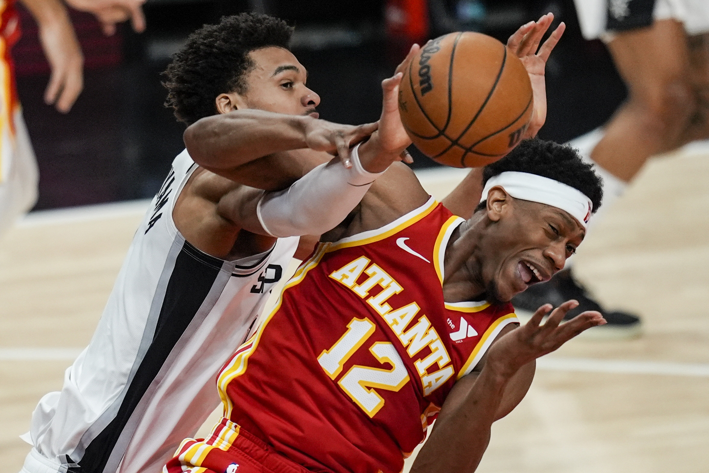 Atlanta Hawks forward De'Andre Hunter (12) and San Antonio Spurs center Victor Wembanyama (1) vie for a loose ball during the first half of an NBA basketball game, Wednesday, Feb. 5, 2025, in Atlanta.