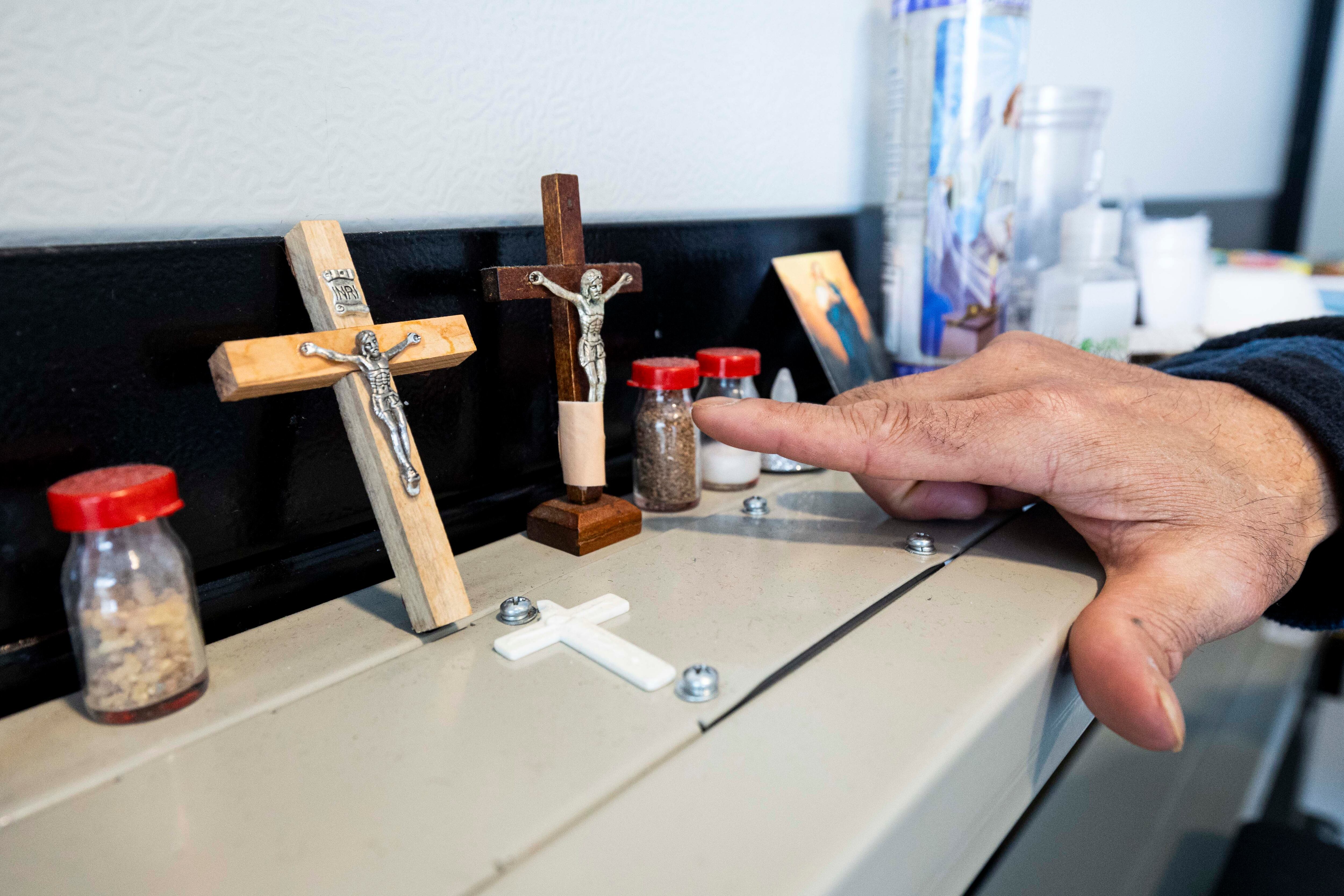 Dixie Nennis points out religious items inside his microshelter unit at a microshelter community operated by Switchpoint in Salt Lake City on Thursday.