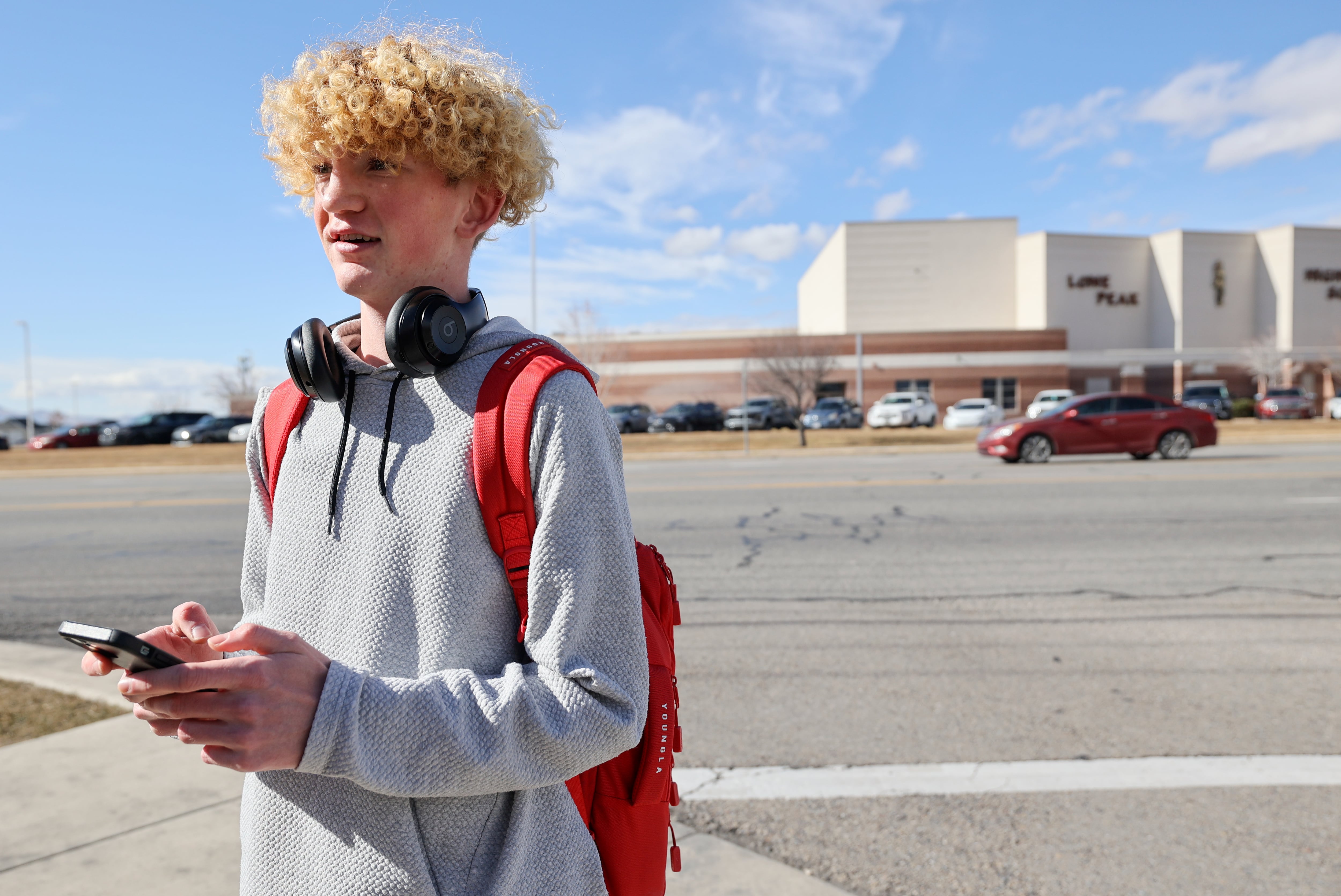 Lone Peak junior Grayson Mcevoy texts his parents for permission to be in the news during his lunch break outside of Lone Peak High School on the border of Highland and Cedar Hills on Thursday.