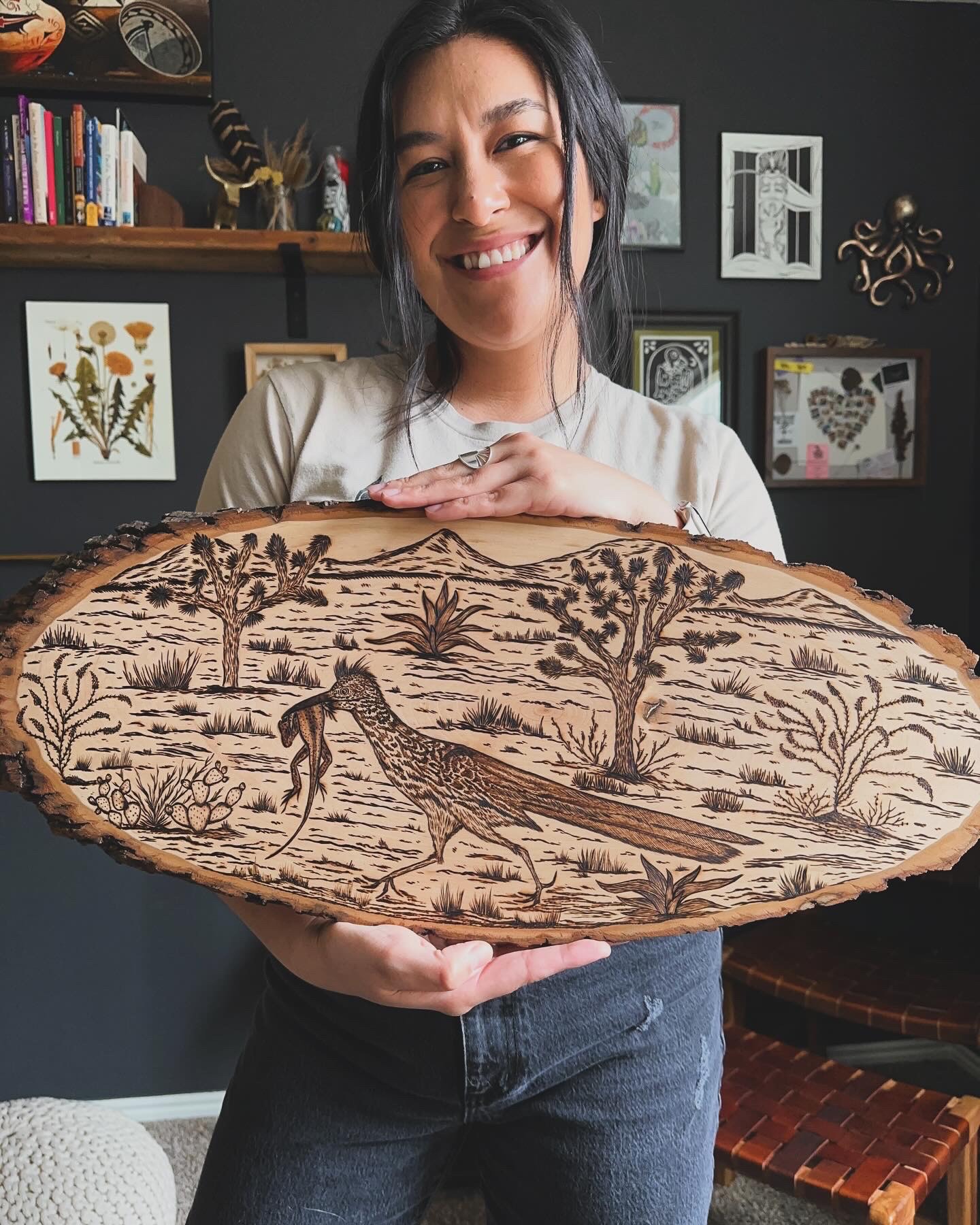 Miriam Gutierrez holds up an original artwork she made with a wood-burning technique.