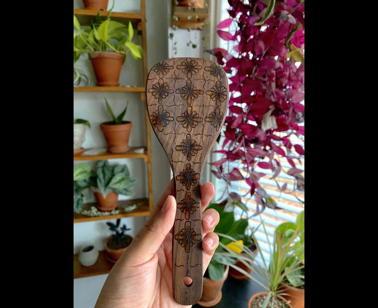 An original wood-burn design on a wooden utensil by Miriam Gutierrez.