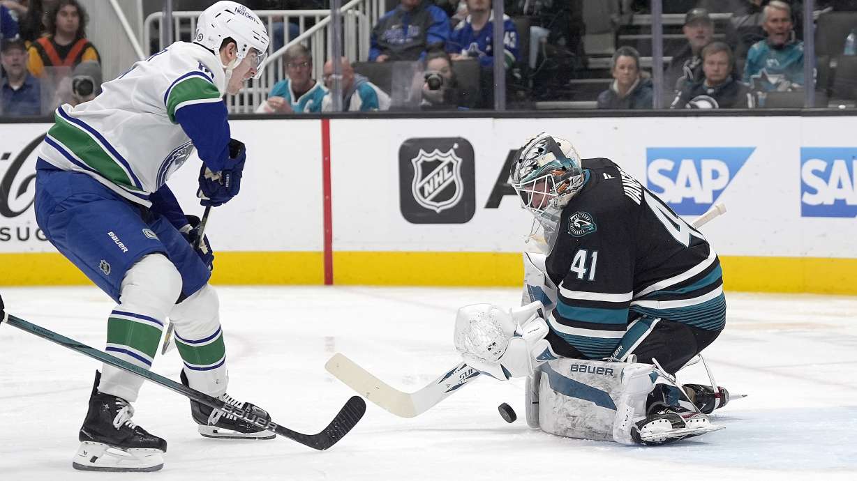 San Jose Sharks goaltender Vitek Vanecek (41) blocks a shot on goal by Vancouver Canucks left wing Drew O'Connor, left, during the second period of an NHL hockey game in San Jose, Calif., Thursday, Feb. 6, 2025.