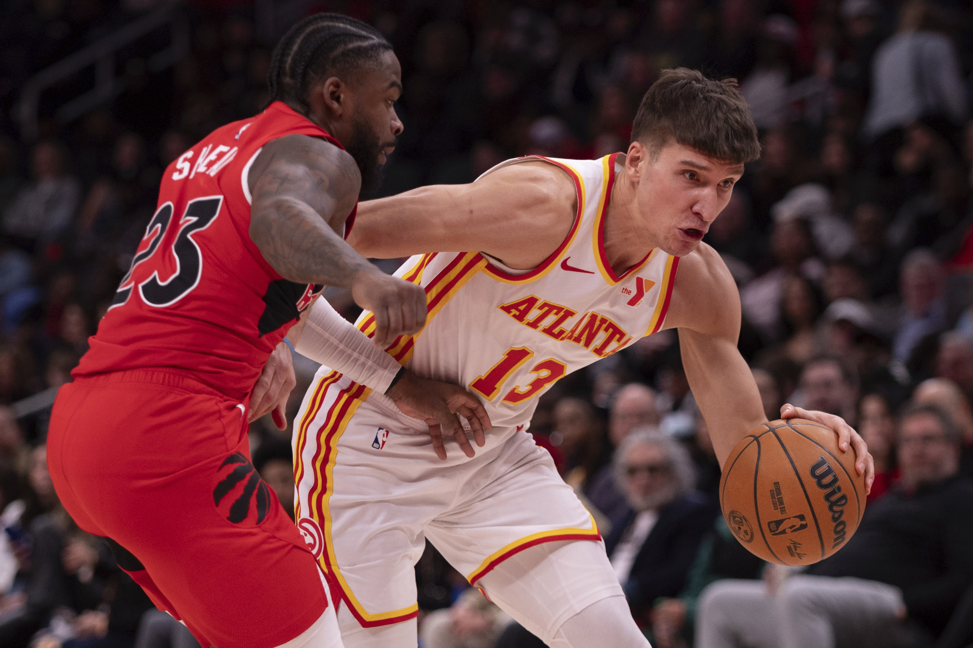 Atlanta Hawks guard Bogdan Bogdanovic (13) drives the ball past Toronto Raptors guard Jamal Shead (23) during the second half of an NBA basketball game, Saturday, Jan. 25, 2025, in Atlanta.