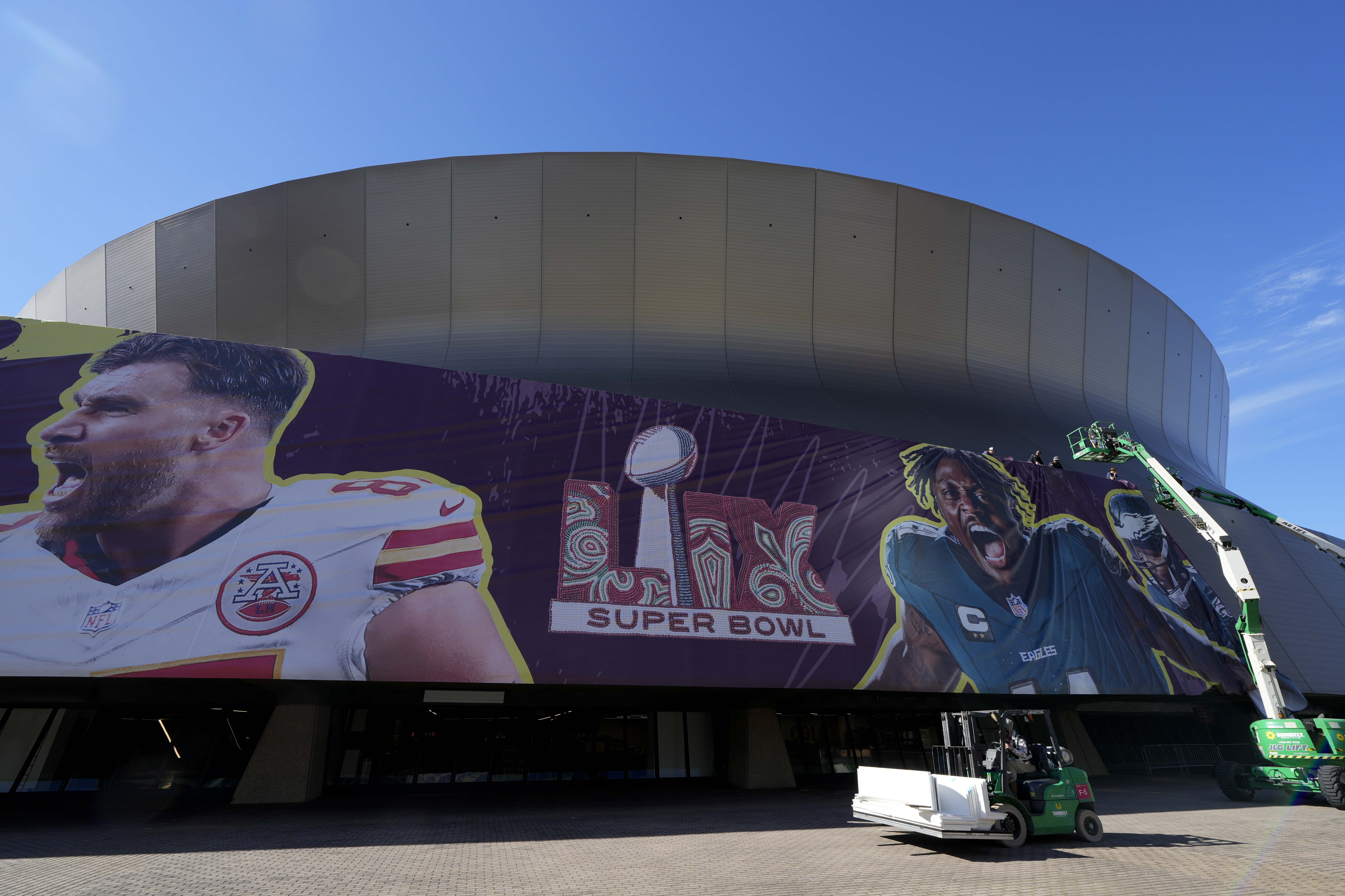 Workers hang player banners outside the Caesars Superdome in New Orleans on Feb. 1, prior to the NFL Super Bowl 59 football game between the Philadelphia Eagles and the Kansas City Chiefs.