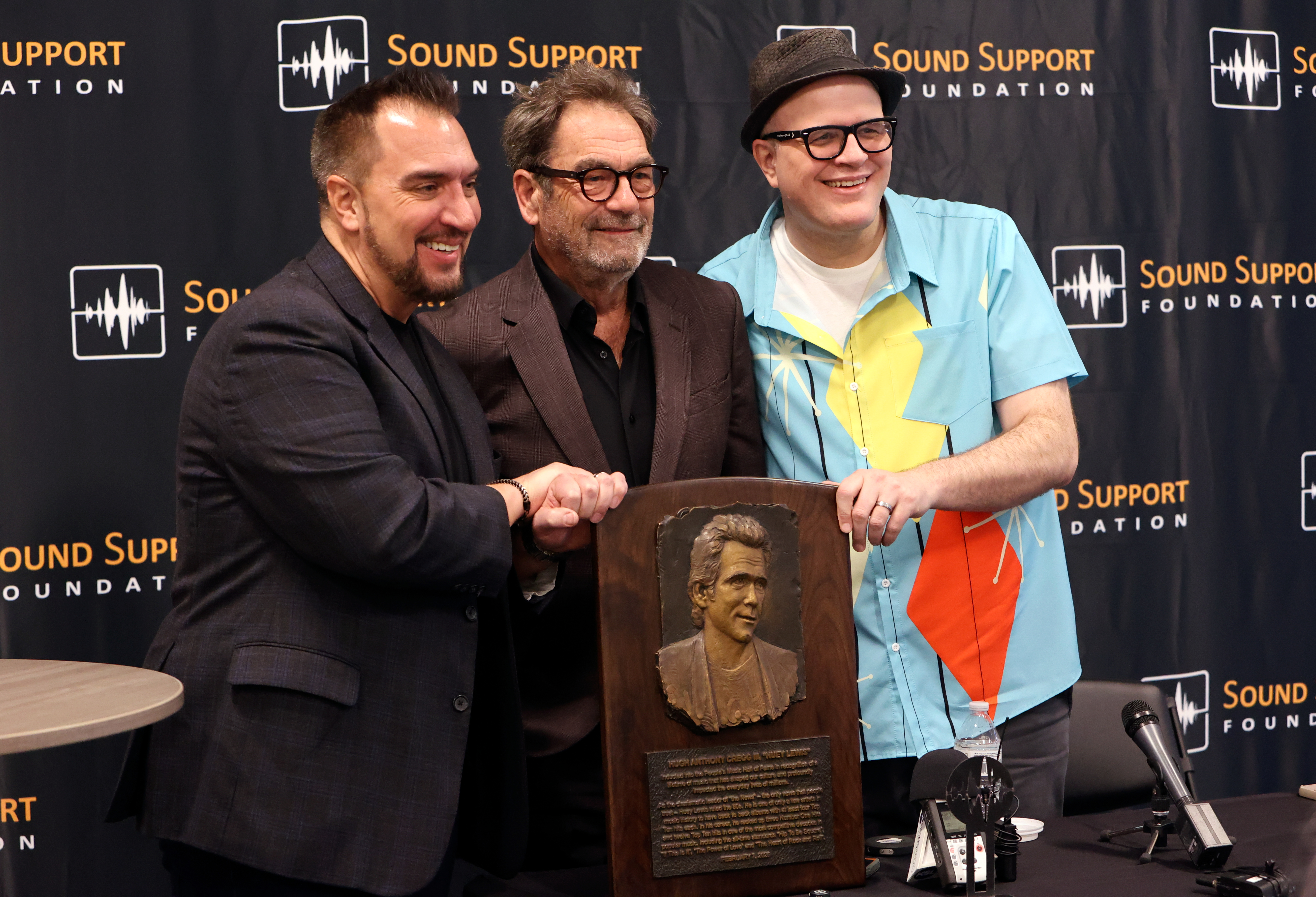Caleb Chapman, Soundhouse founder and CEO, Huey Lewis and Adam Reader, Professor of Rock, pose for a photo during a press conference ahead of Lewis’s induction into the People’s Music Hall of Fame at the Eccles Theater in Salt Lake City on Friday.