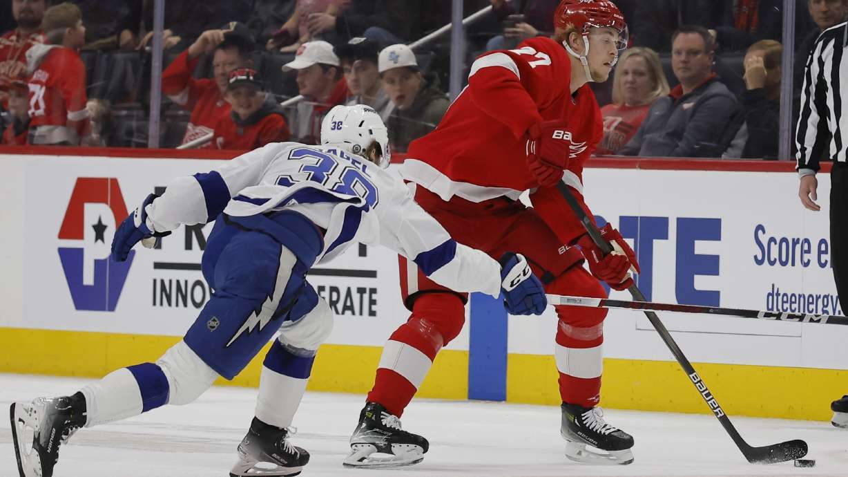 Detroit Red Wings center Michael Rasmussen (27) passes the puck while being guarded by Tampa Bay Lightning left wing Brandon Hagel (38) during the first period of an NHL hockey game Saturday, Jan. 25, 2025, in Detroit.