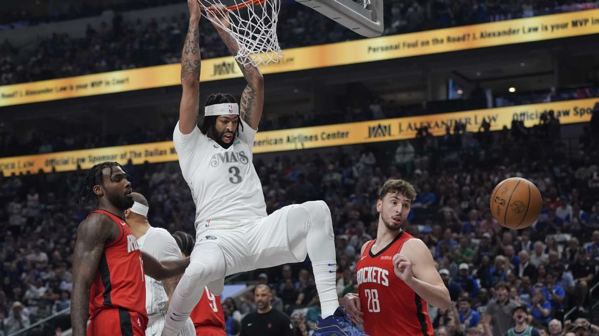 Dallas Mavericks forward Anthony Davis (3) hangs on the rim after dunking on Houston Rockets forward Tari Eason (17) and center Alperen Sengun (28) during the first half of an NBA basketball game Saturday, Feb. 8, 2025, in Dallas.