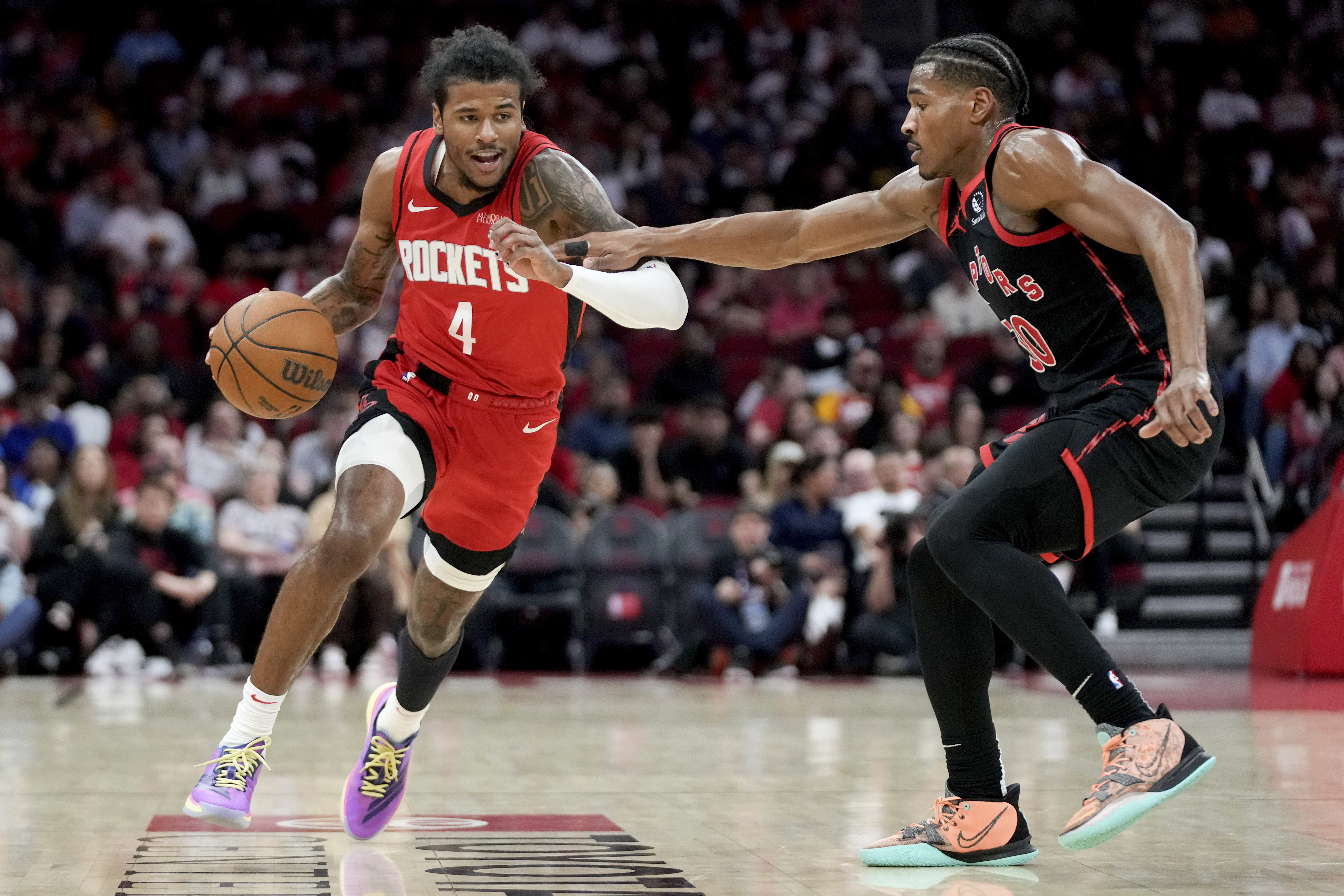 Houston Rockets guard Jalen Green (4) dribbles as Toronto Raptors guard Ochai Agbaji, right, defends during the first half of an NBA basketball game Sunday, Feb. 9, 2025, in Houston.