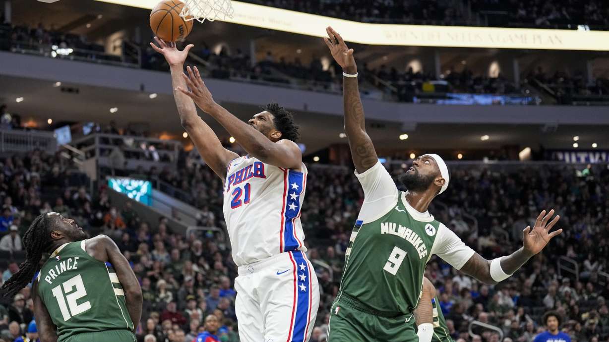 Philadelphia 76ers' Joel Embiid (21) shoots between Milwaukee Bucks' Taurean Prince (12) and Bobby Portis Jr. (9) during the first half of an NBA basketball game Sunday, Feb. 9, 2025, in Milwaukee.