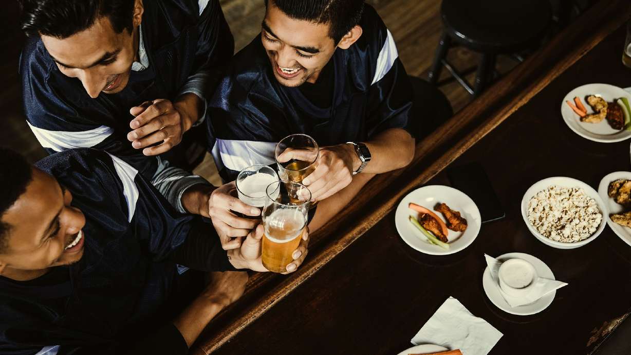 High angle view of excited sports fans toasting beer glasses at a bar.