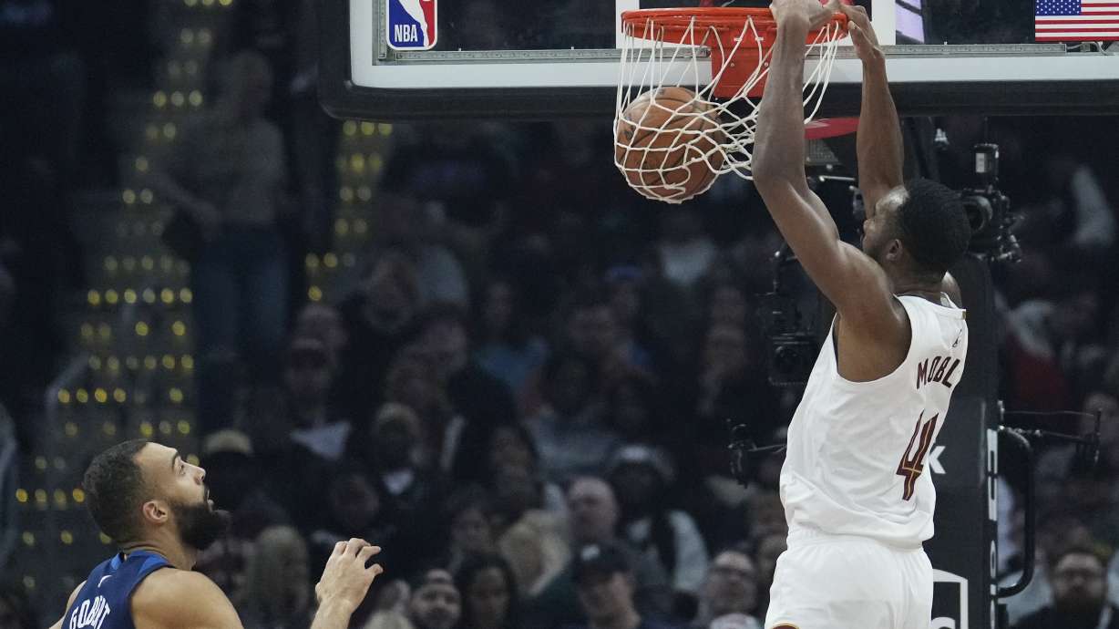 Cleveland Cavaliers forward Evan Mobley, right, dunks in front of Minnesota Timberwolves center Rudy Gobert, left, in the first half of an NBA basketball game Monday, Feb. 10, 2025, in Cleveland.