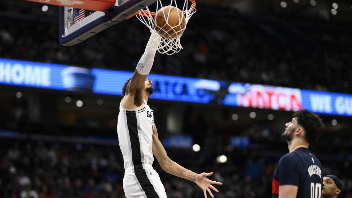 San Antonio Spurs center Victor Wembanyama, left, dunks past Washington Wizards forward Tristan Vukcevic (00) during the first half of an NBA basketball game, Monday, Feb. 10, 2025, in Washington.