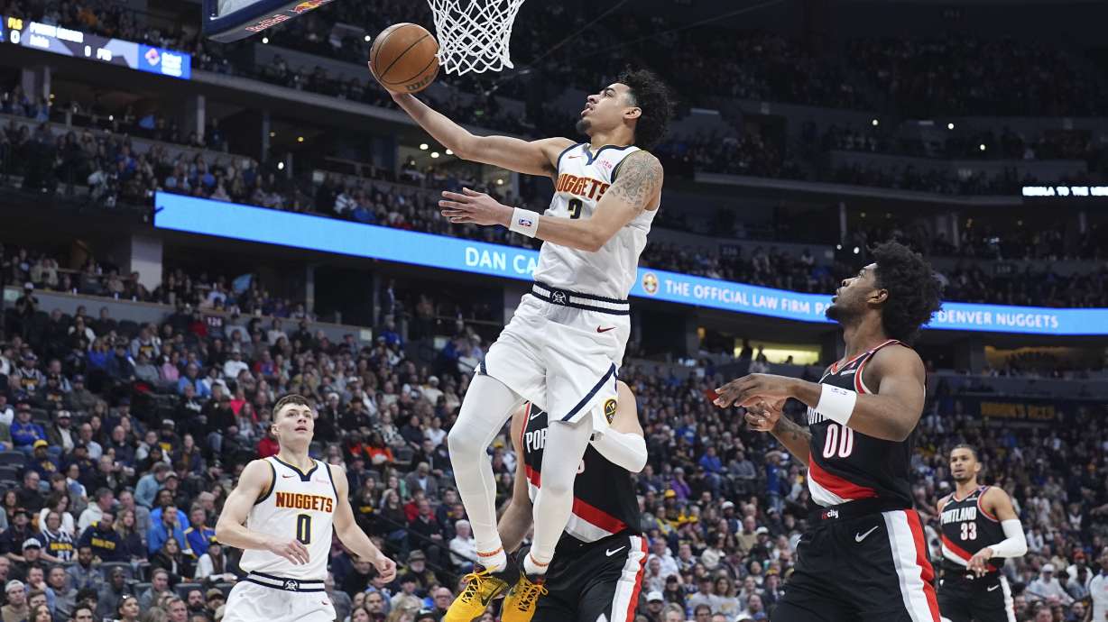 Denver Nuggets guard Julian Strawther, center top, drives to the basket as Portland Trail Blazers guard Scoot Henderson (00) defends in the first half of an NBA basketball game Monday, Feb. 10, 2025, in Denver.