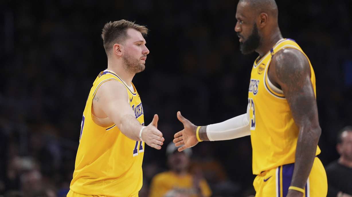 Los Angeles Lakers guard Luka Doncic, left, touches hands with teammate forward LeBron James during the first half of an NBA basketball game against the Utah Jazz, Monday, Feb. 10, 2025, in Los Angeles.