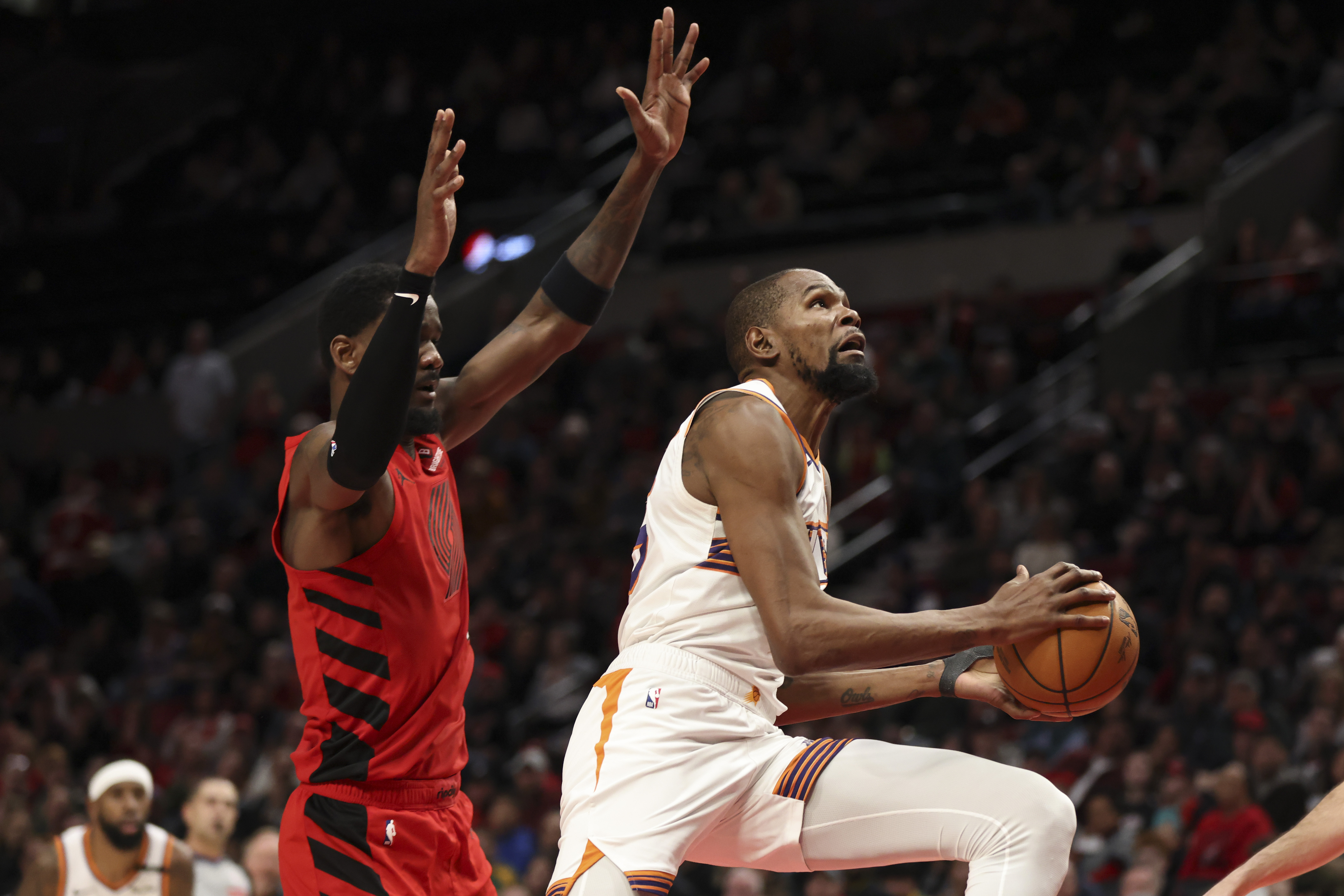 Phoenix Suns forward Kevin Durant, right, drives to the basket past Portland Trail Blazers center Deandre Ayton during overtime of an NBA basketball game Monday, Feb. 3, 2025, in Portland, Ore.