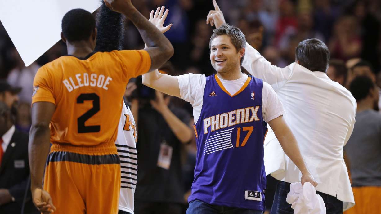 FILE - Phoenix Suns' Eric Bledsoe (2) high fives fan Tim Boven after Boven hit a three point field goal for $77,777 during a time out during the first half of an NBA basketball game against the New York Knicks, Friday, March 28, 2014, in Phoenix.