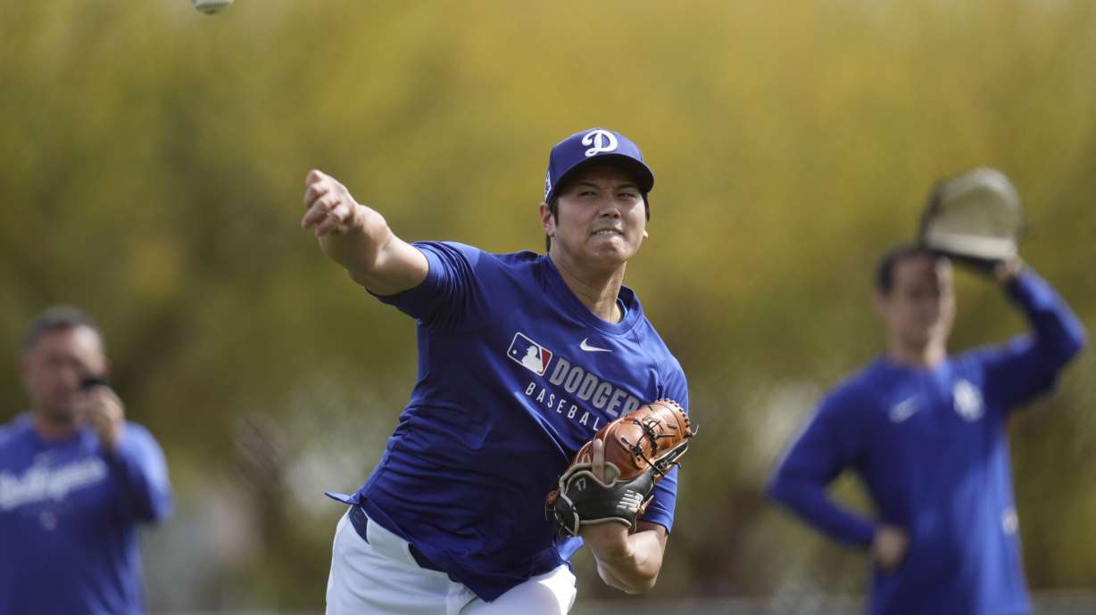 Los Angeles Dodgers' Shohei Ohtani, of Japan, warms up with other pitchers and catchers at the Dodgers baseball spring training facility, Tuesday, Feb. 11, 2025, in Phoenix.