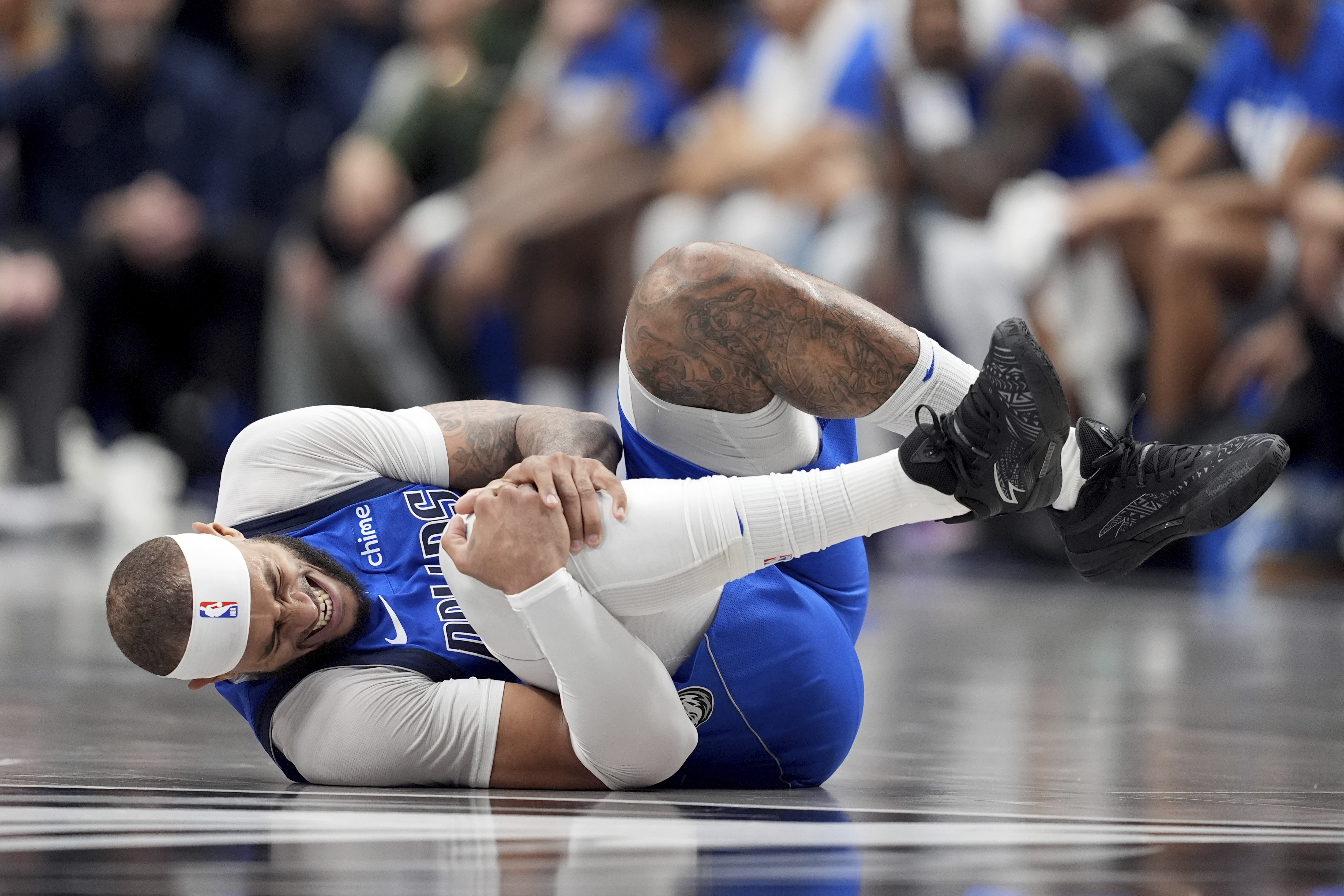 Dallas Mavericks center Daniel Gafford grabs his knee after suffering an unknown injury in the first half of an NBA basketball game against the Sacramento Kings in Dallas, Monday, Feb. 10, 2025.