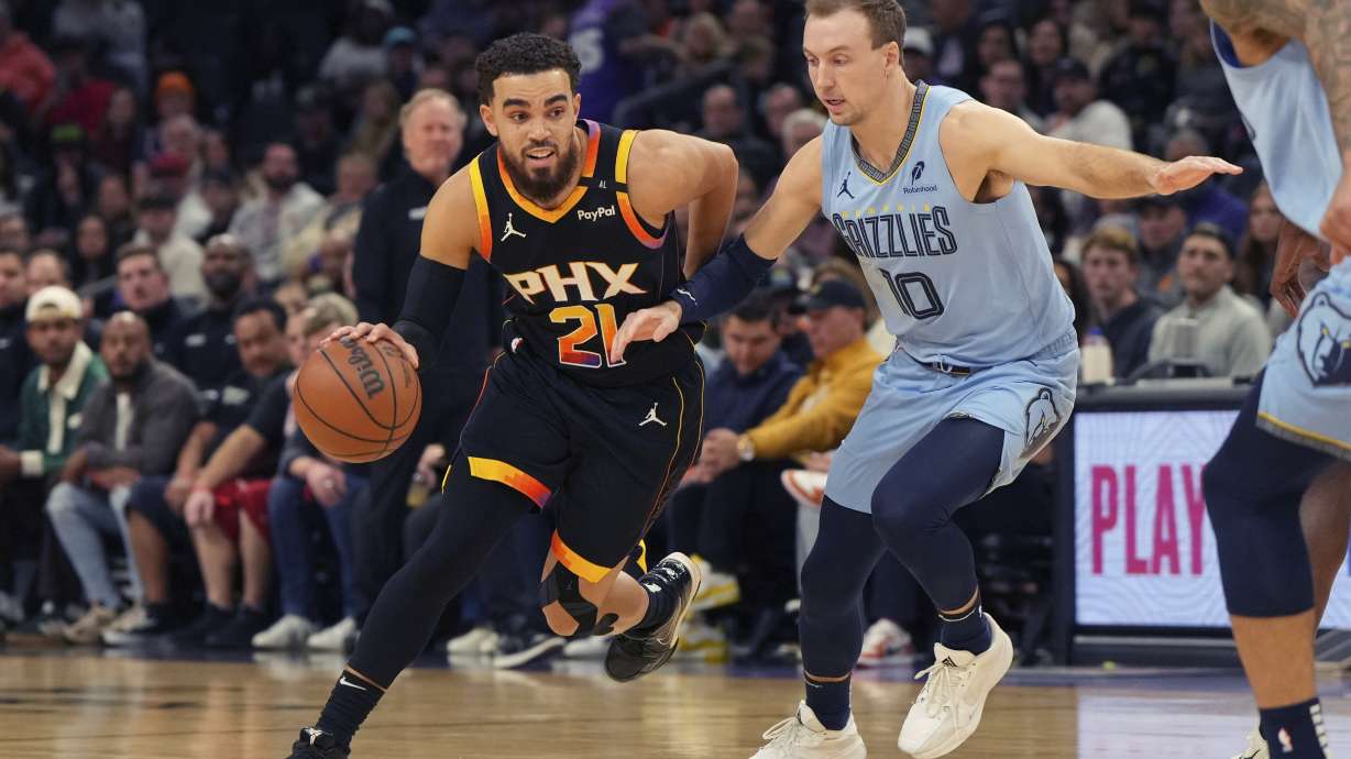Phoenix Suns guard Tyus Jones (21) drives on Memphis Grizzlies guard Luke Kennard during the first half of an NBA basketball game, Tuesday, Feb. 11, 2025, in Phoenix.
