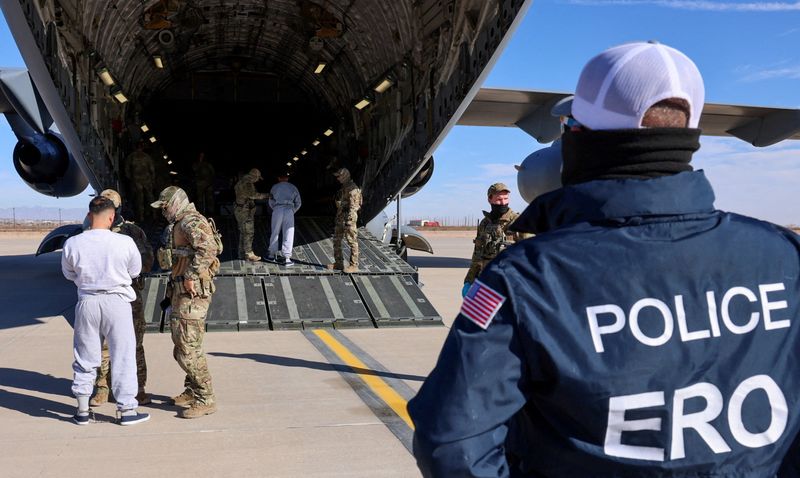 The first U.S. military aircraft to carry detained migrants to a detention facility at Guantanamo Bay, is boarded from an unspecified location in the Feb. 4. handout. The ACLU filed a lawsuit on Wednesday seeking access to dozens of migrants flown to the naval base.