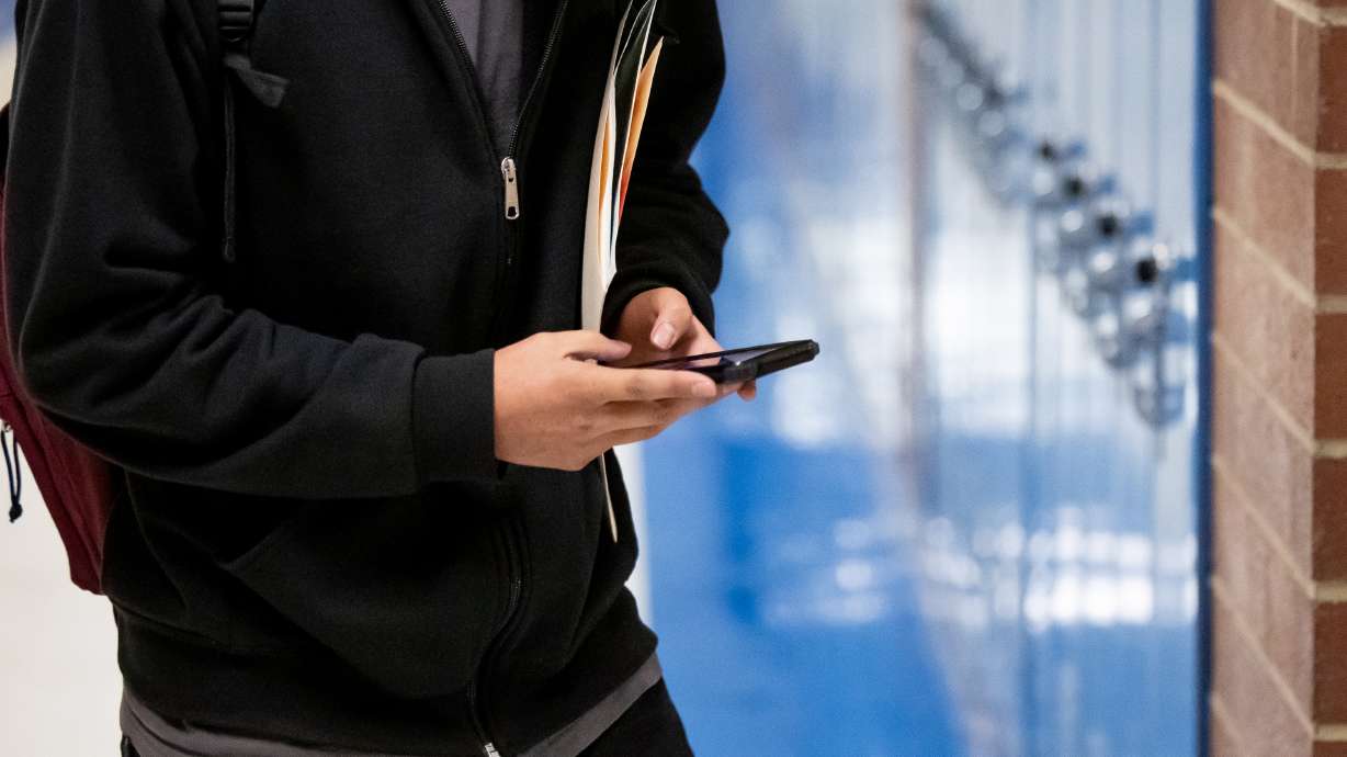 A student uses their phone while walking between classes at Cyprus High School in Magna on Jan. 27, 2023. Utah senators unanimously passed a bill prohibiting the use of cellphones and smart watches in K-12 classrooms across the state.