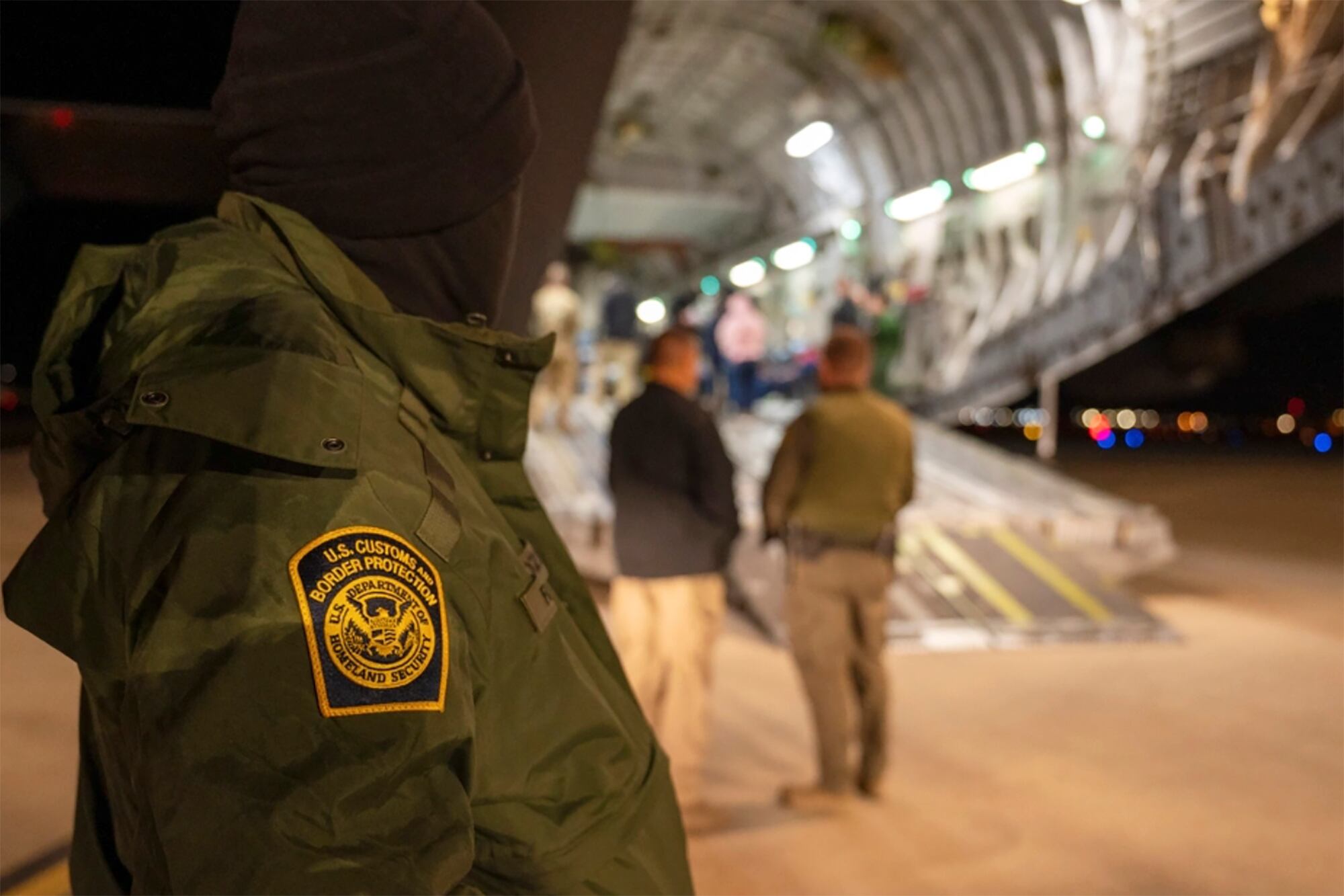 A U.S. Customs and Border Protection agent watches as immigrants who were living in the country illegally are loaded onto a C-17 Globemaster III at Tucson International Airport in Tucson, Ariz., Jan. 23.