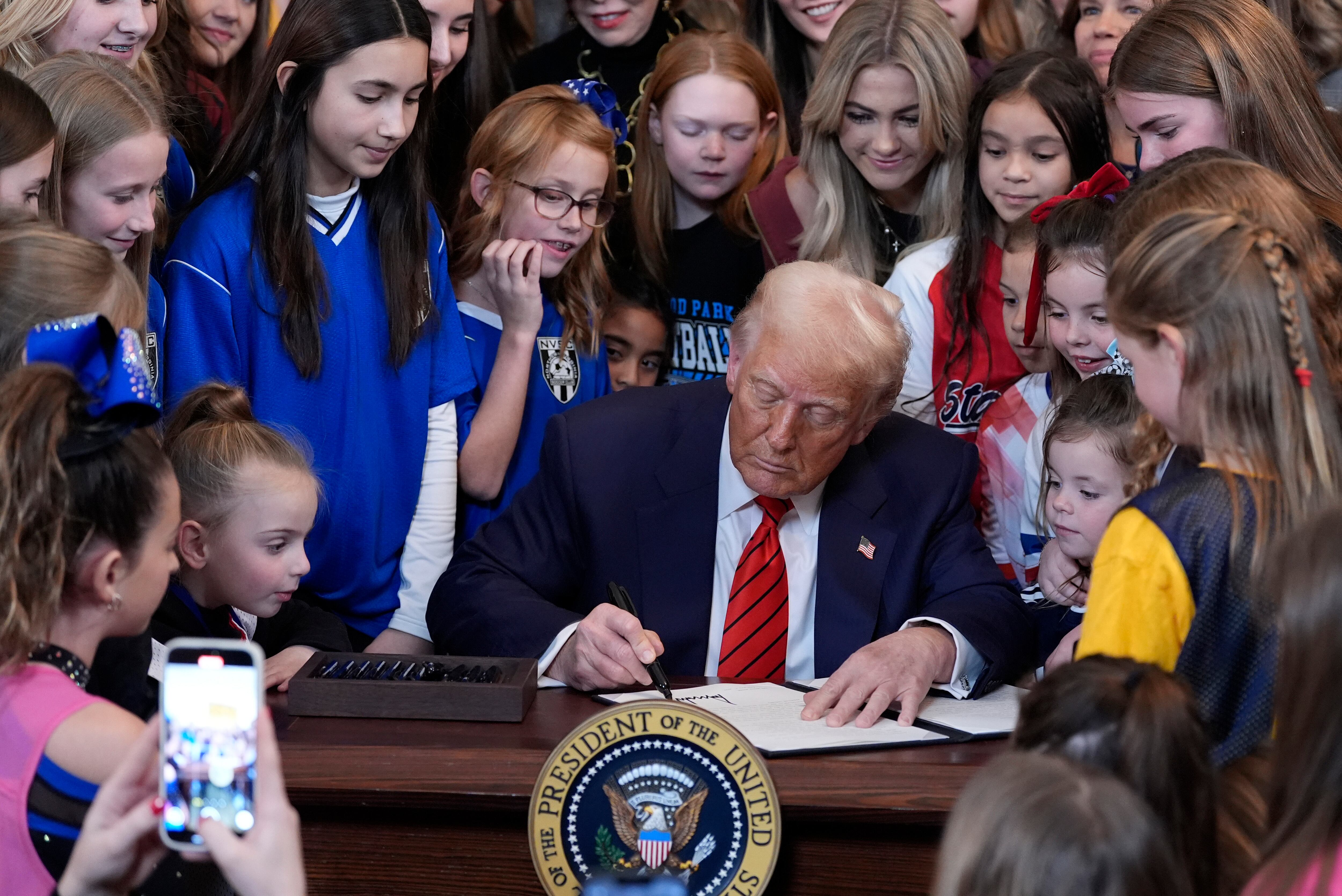 President Donald Trump signs an executive order barring transgender female athletes from competing in women's or girls' sporting events, in the East Room of the White House, Feb. 5, 2025, in Washington.