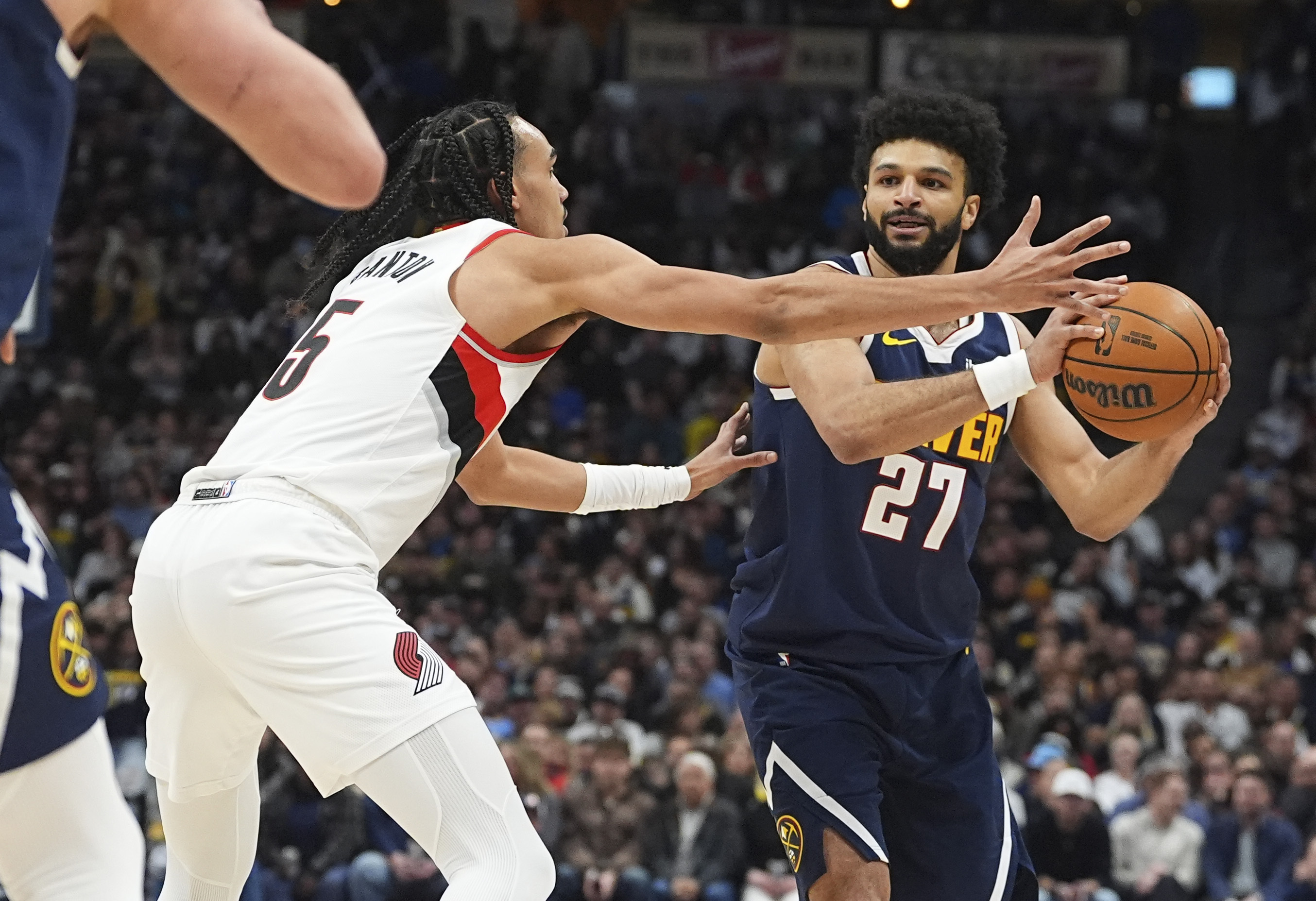 Denver Nuggets guard Jamal Murray, right, looks to pass the ball as Portland Trail Blazers guard Dalano Banton defends in the first half of an NBA basketball game Wednesday, Feb. 12, 2025, in Denver.