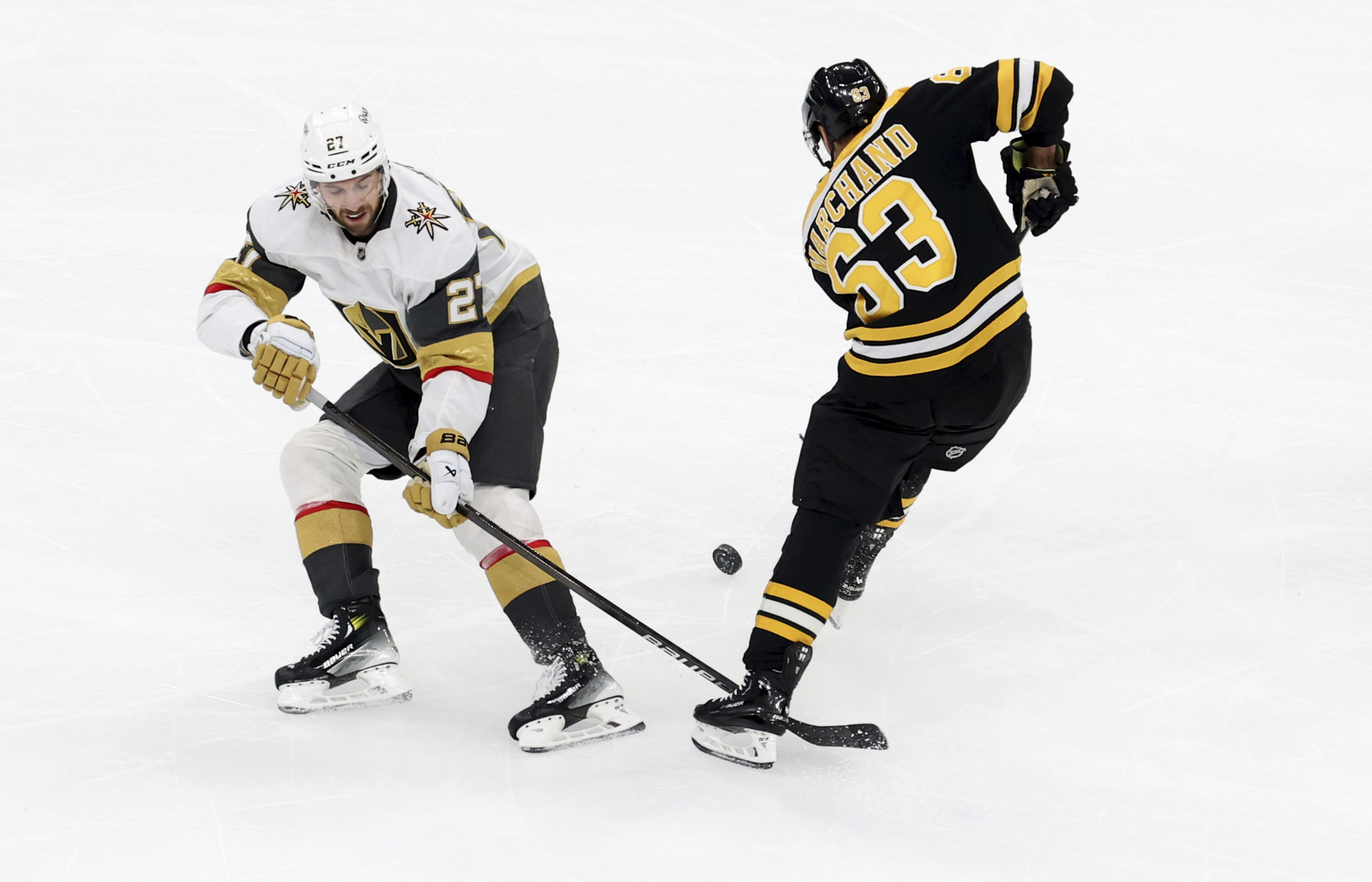 Vegas Golden Knights defenseman Shea Theodore (27) and Boston Bruins left wing Brad Marchand (63) battle for the puck during the second period of an NHL hockey game, Saturday, Feb. 8, 2025, in Boston.