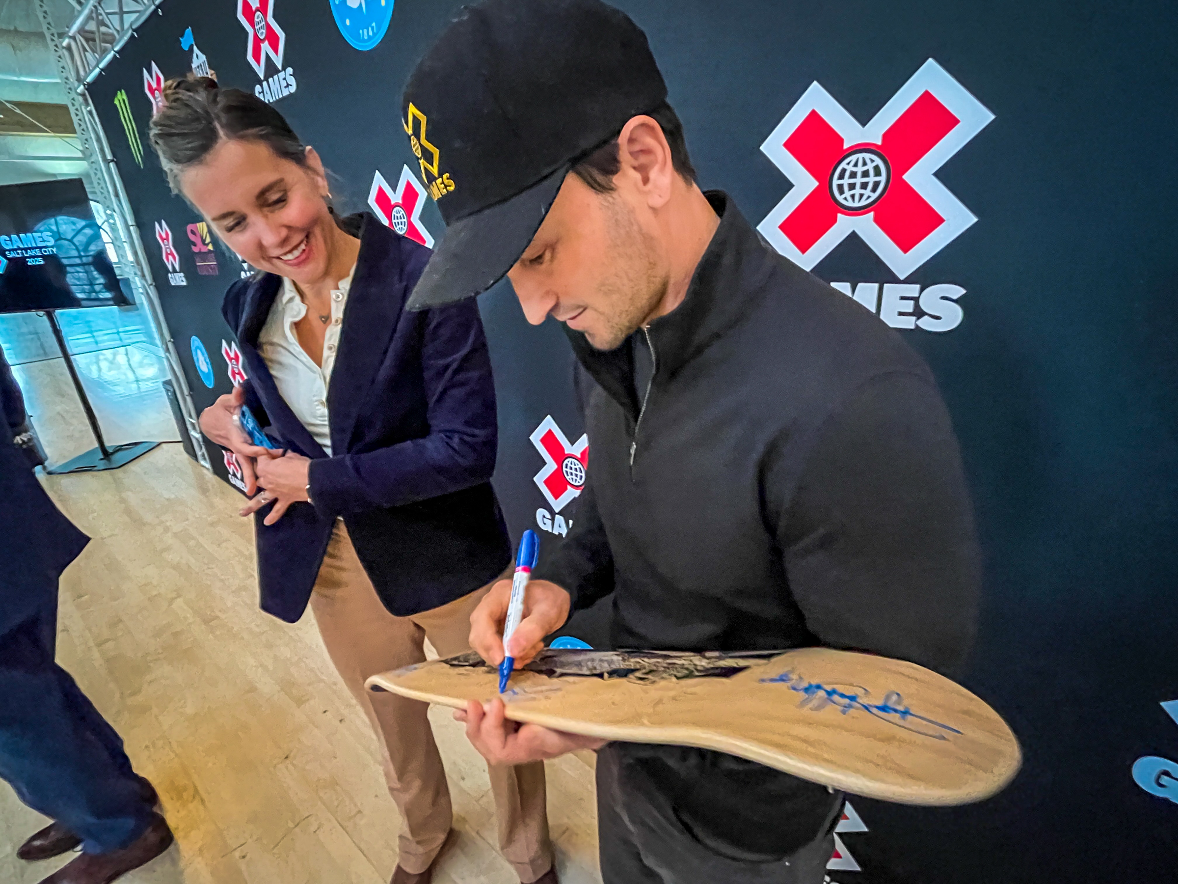 X Games CEO Jeremy Bloom signs a Salt Lake City-themed skateboard deck for Salt Lake City Mayor Erin Mendenhall after a press conference Thursday announcing X Games will come to Salt Lake City at the Utah State Fairpark in June.