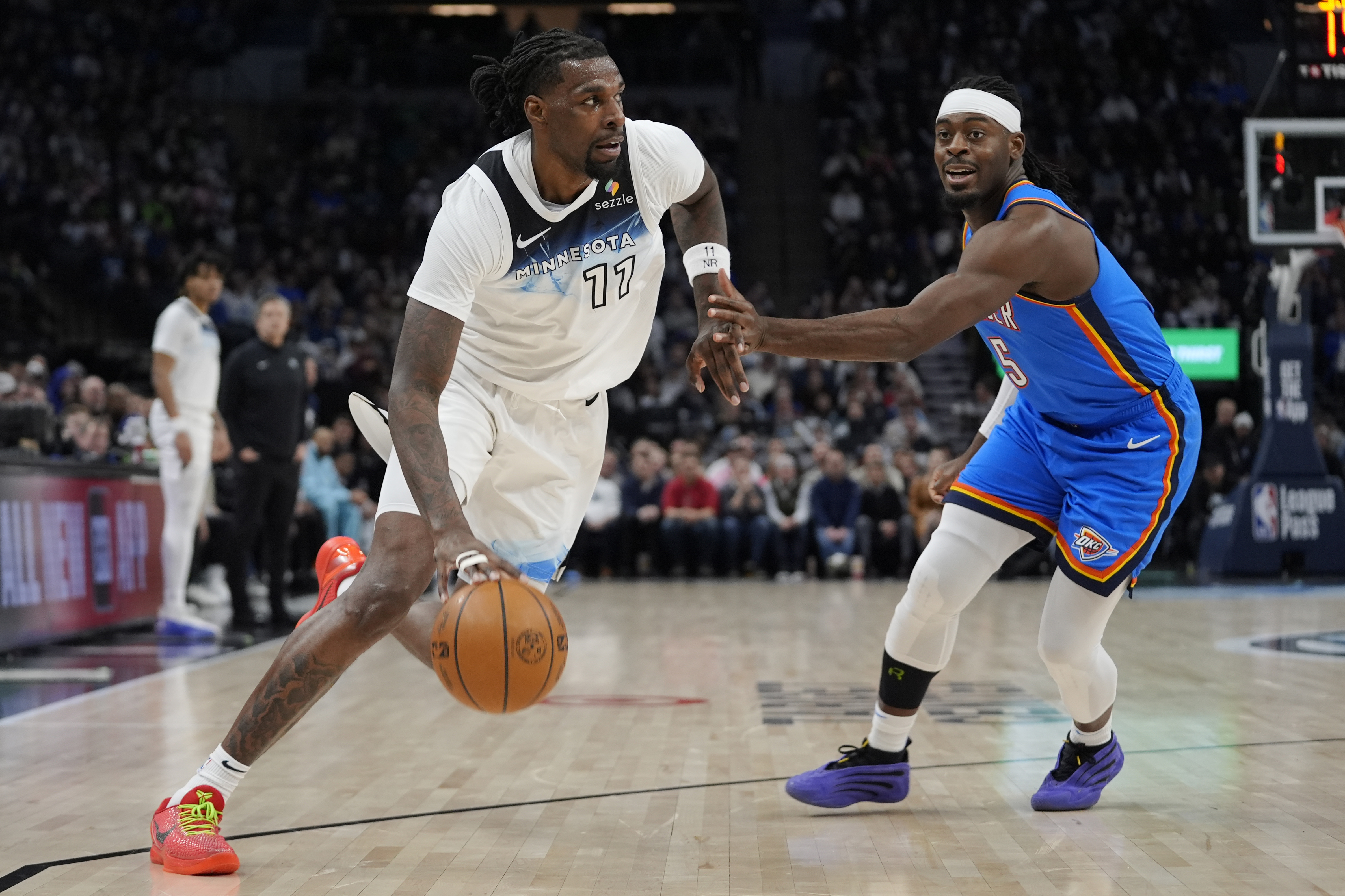 Minnesota Timberwolves center Naz Reid (11) works toward the basket as Oklahoma City Thunder guard Luguentz Dort (5) defends during the first half of an NBA basketball game, Thursday, Feb. 13, 2025, in Minneapolis.