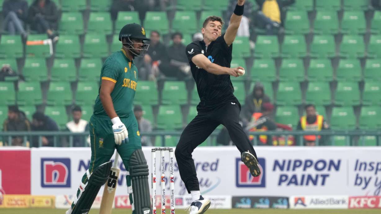 New Zealand's Ben Sears, right, bowls as South Africa's Jason Smith watches during the tri-series ODI cricket match between New Zealand and South Africa, in Lahore, Pakistan, Monday, Feb. 10, 2025.