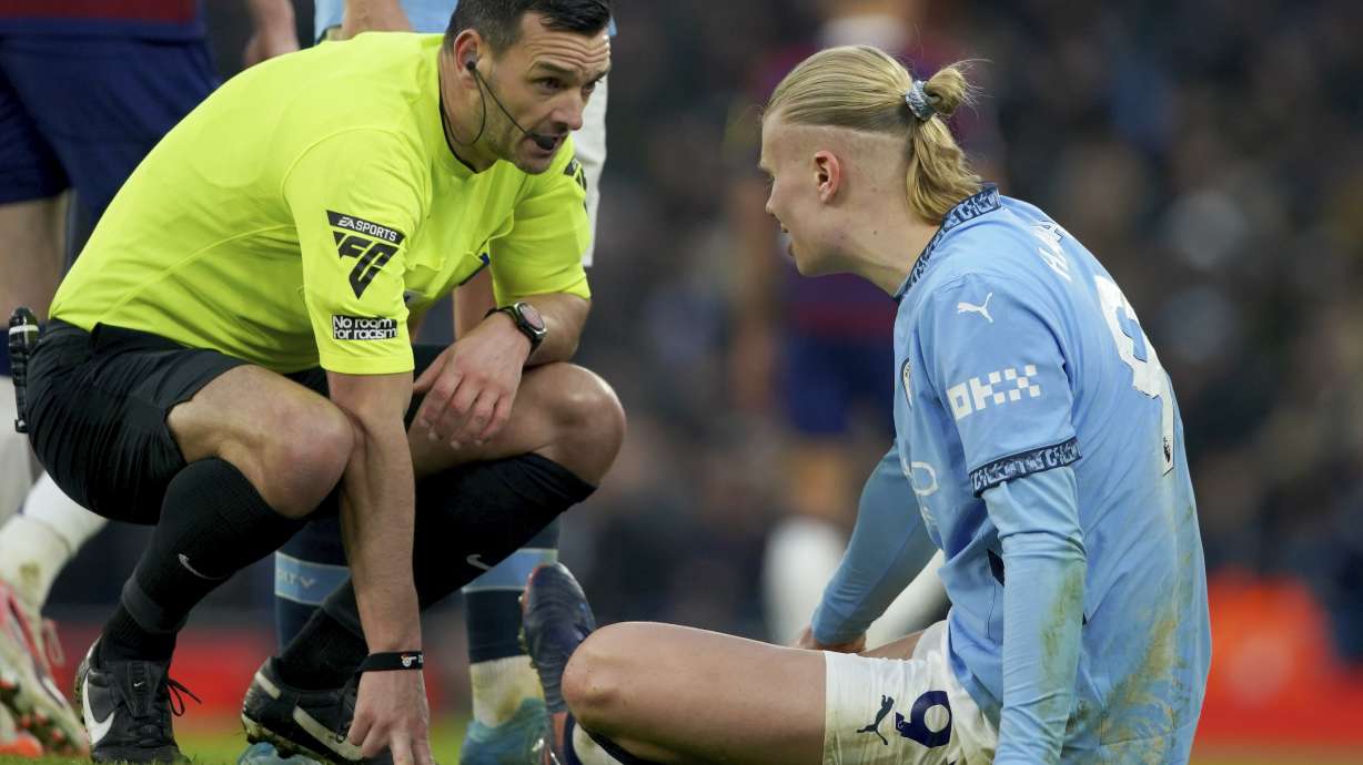 Referee Andy Madley checks on Manchester City's Erling Haaland after he injured himself during the English Premier League soccer match between Manchester City and Newcastle United at Etihad stadium in Manchester, England, Saturday, Feb. 15, 2025.
