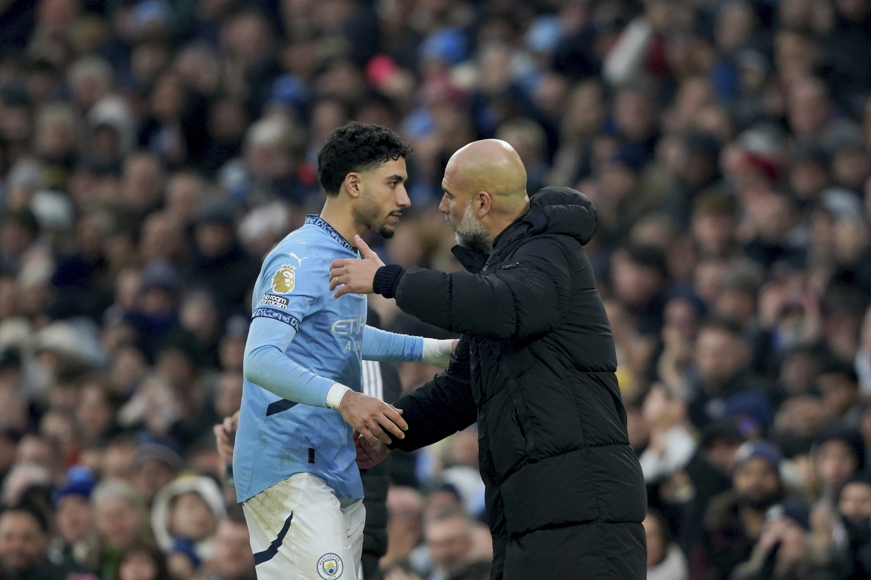 Manchester City's head coach Pep Guardiola embraces Manchester City's Omar Marmoush as he leaves the pitch after being replaced during the English Premier League soccer match between Manchester City and Newcastle United at Etihad stadium in Manchester, England, Saturday, Feb. 15, 2025.