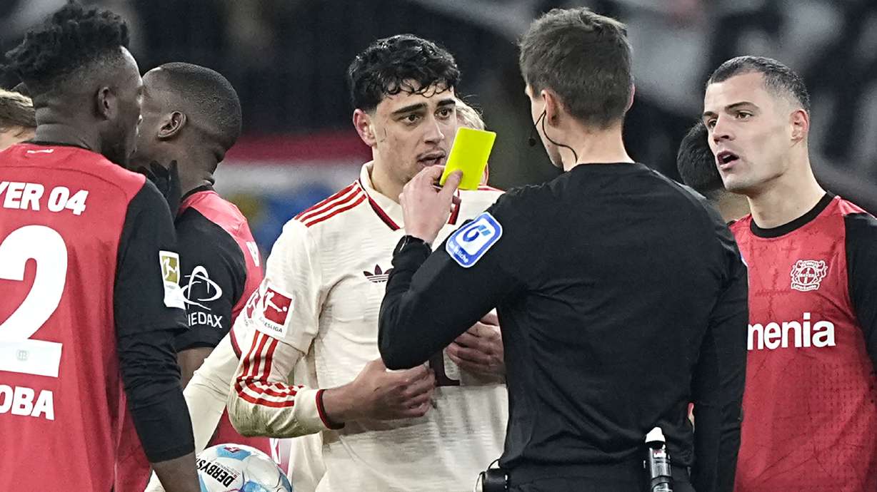Referee Samuel Barrott shows a yellow card to Bayern's Aleksandar Pavlovic during the German Bundesliga soccer match between Bayer Leverkusen and FC Bayern Munich at the BayArena in Leverkusen, Germany, Saturday, Feb. 15, 2025.