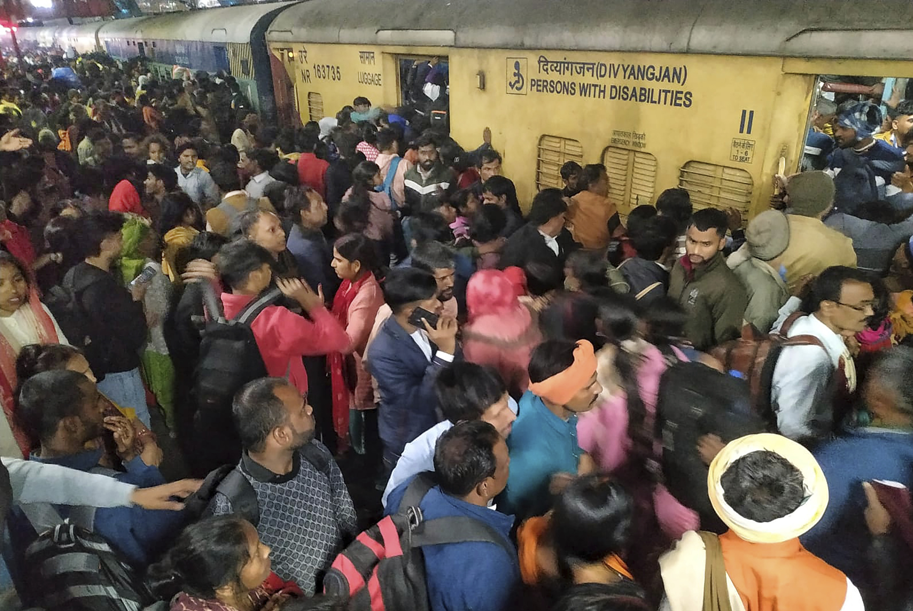 Passengers jostle with each other to board a train at the New Delhi Railway station, in New Delhi, India, Thursday.