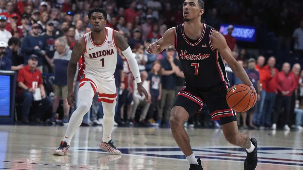 Houston guard Milos Uzan (7) drives past Arizona guard Caleb Love during the first half of an NCAA college basketball game, Saturday, Feb. 15, 2025, in Tucson, Ariz.