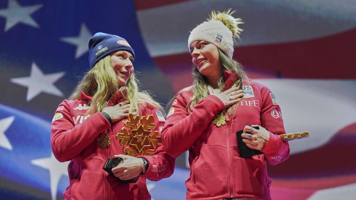 United States' Mikaela Shiffrin, left, and United States' Breezy Johnson listen to the national anthem as they wear their gold medals for a women's team combined event, at the Alpine Ski World Championships, in Saalbach-Hinterglemm, Austria, Tuesday, Feb. 11, 2025.